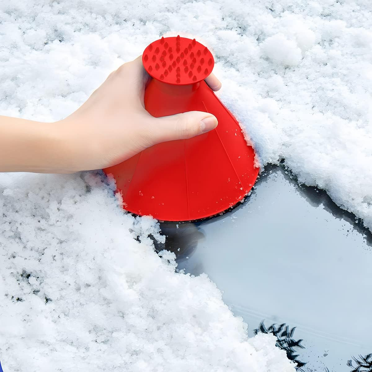 Rote Schnee-Eiskratzer-Bürste wird von einer Hand gehalten, um Schnee vom Glas zu entfernen.