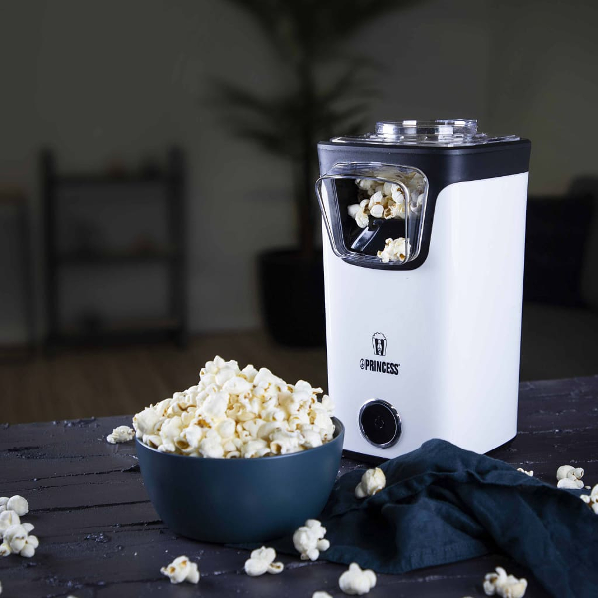 Una macchina per popcorn bianca con una ciotola di popcorn su un tavolo.