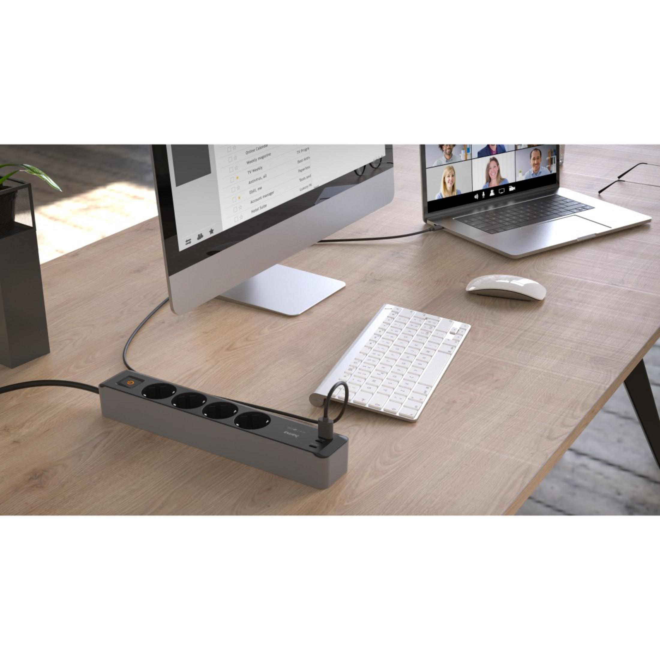 Schreibtisch mit Laptop, Monitor, Tastatur, Maus und Steckdosenleiste.