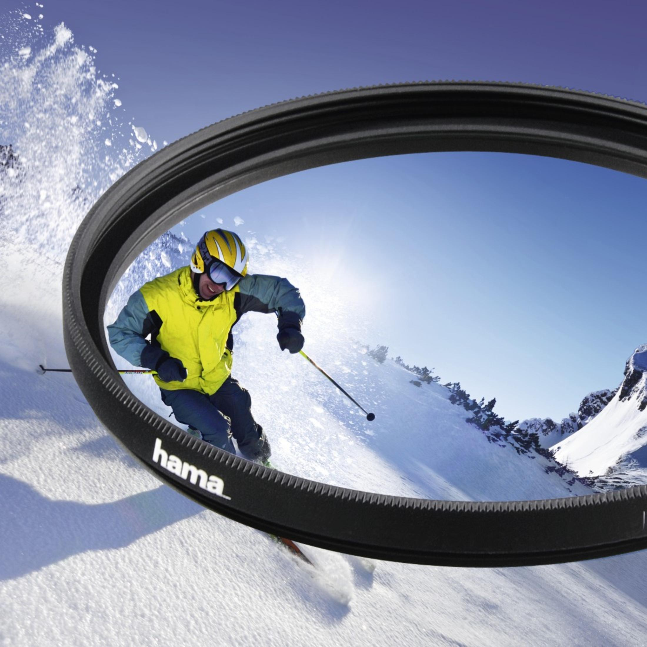Skifahrer in gelber Jacke fährt bergab; Hama-Filter im Vordergrund.