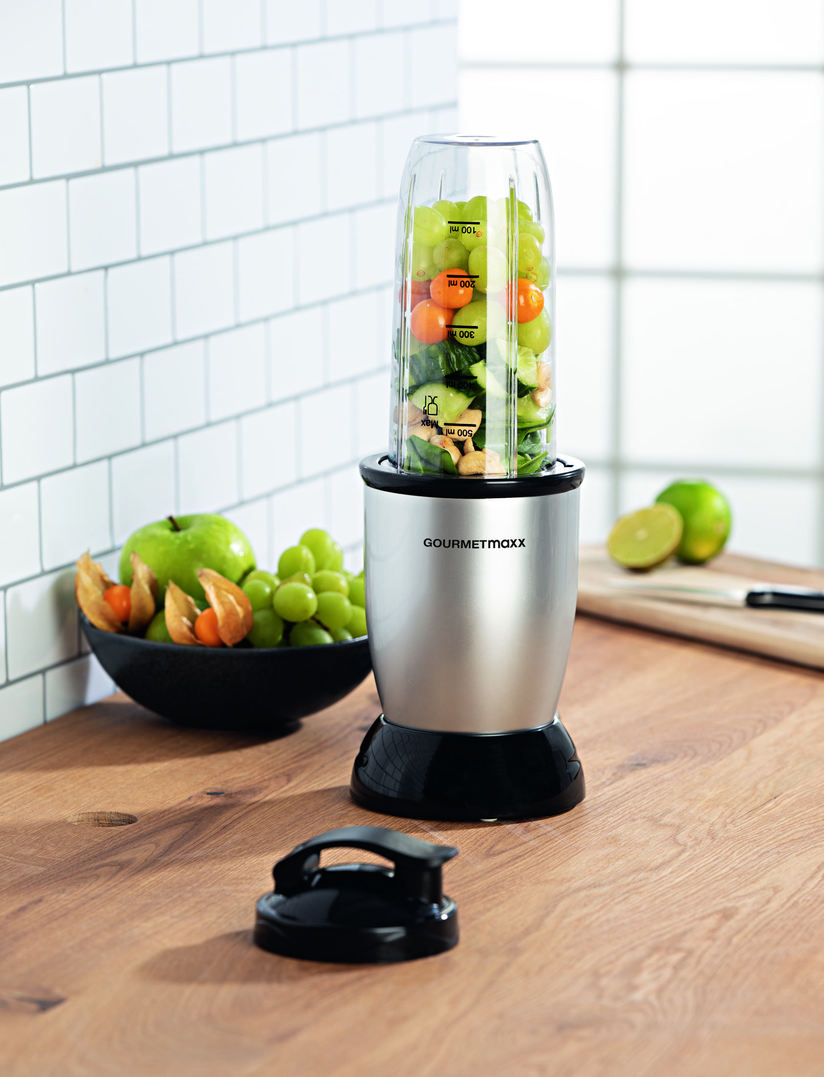 Ein Smoothie-Mixer steht auf einem Holztisch mit Obst und Gemüse.