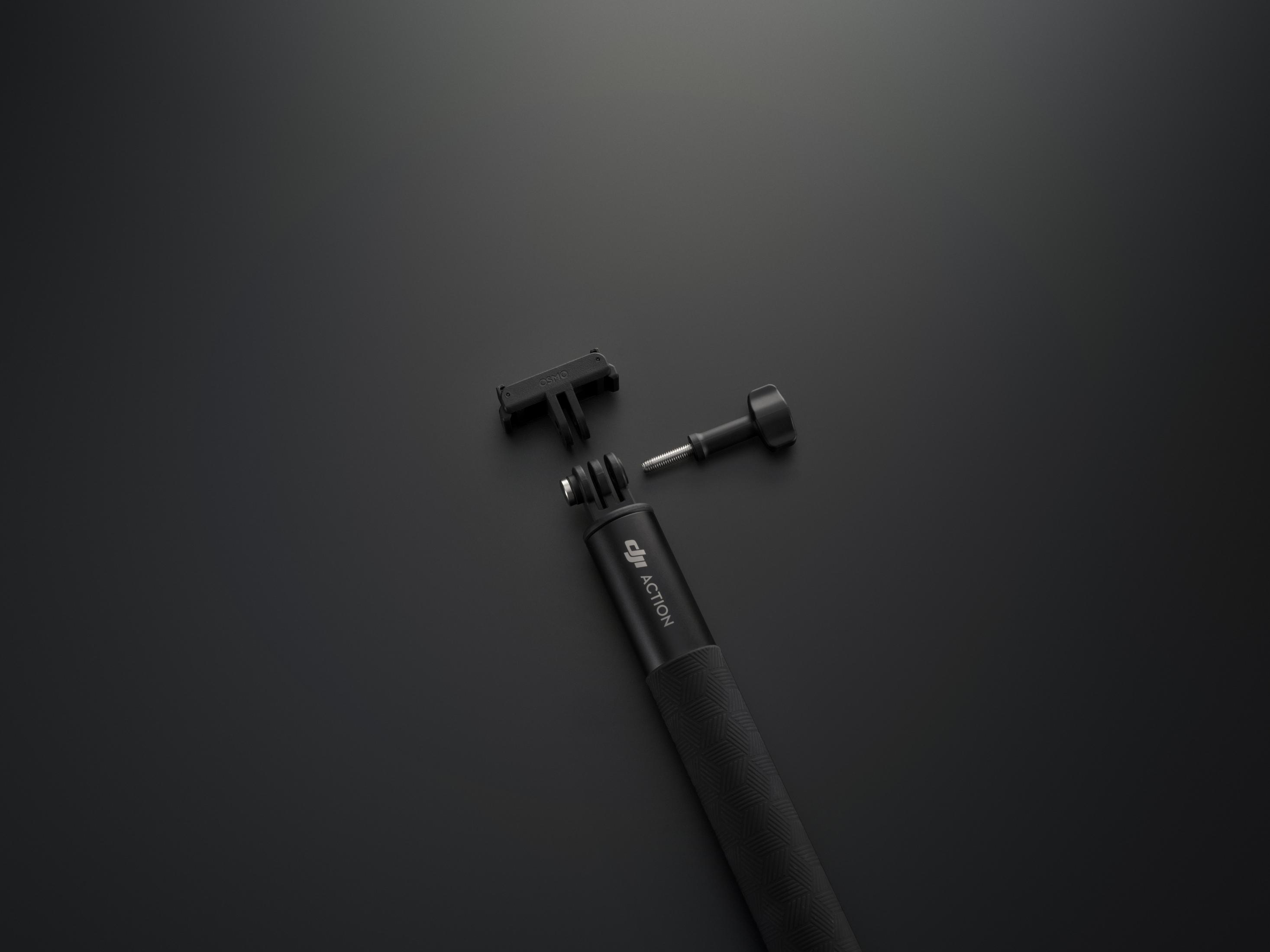 Un mango negro DJI Action con accesorios sobre fondo negro.