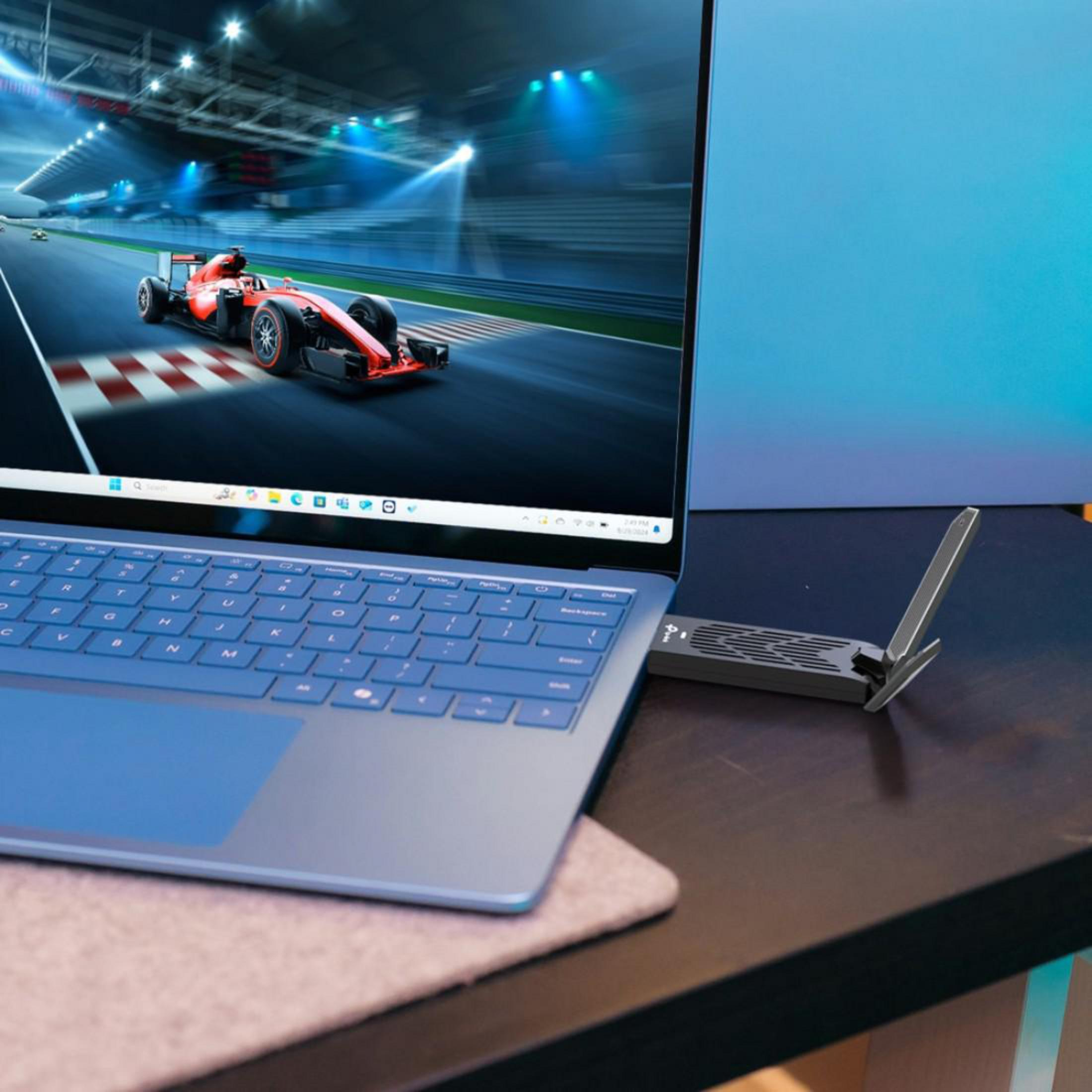Un'auto da corsa su una pista è visualizzata su un laptop. Un piccolo dispositivo è collegato.
