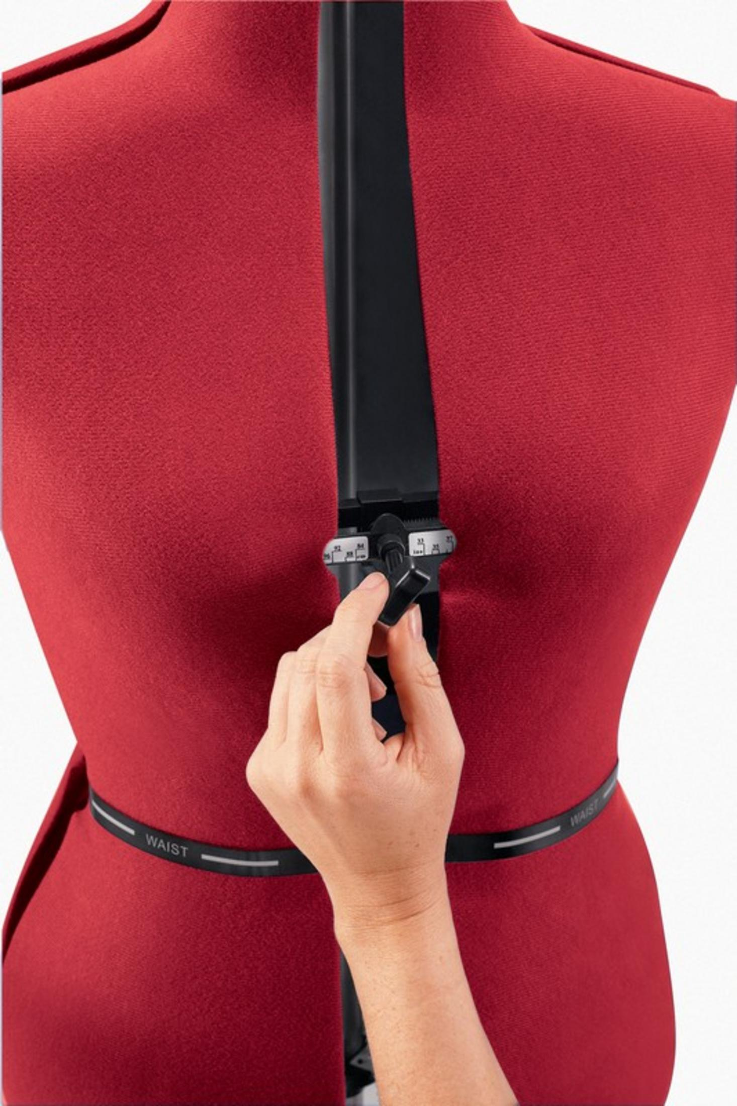 Una mano regola una manopola su un torso da sarta rosso.