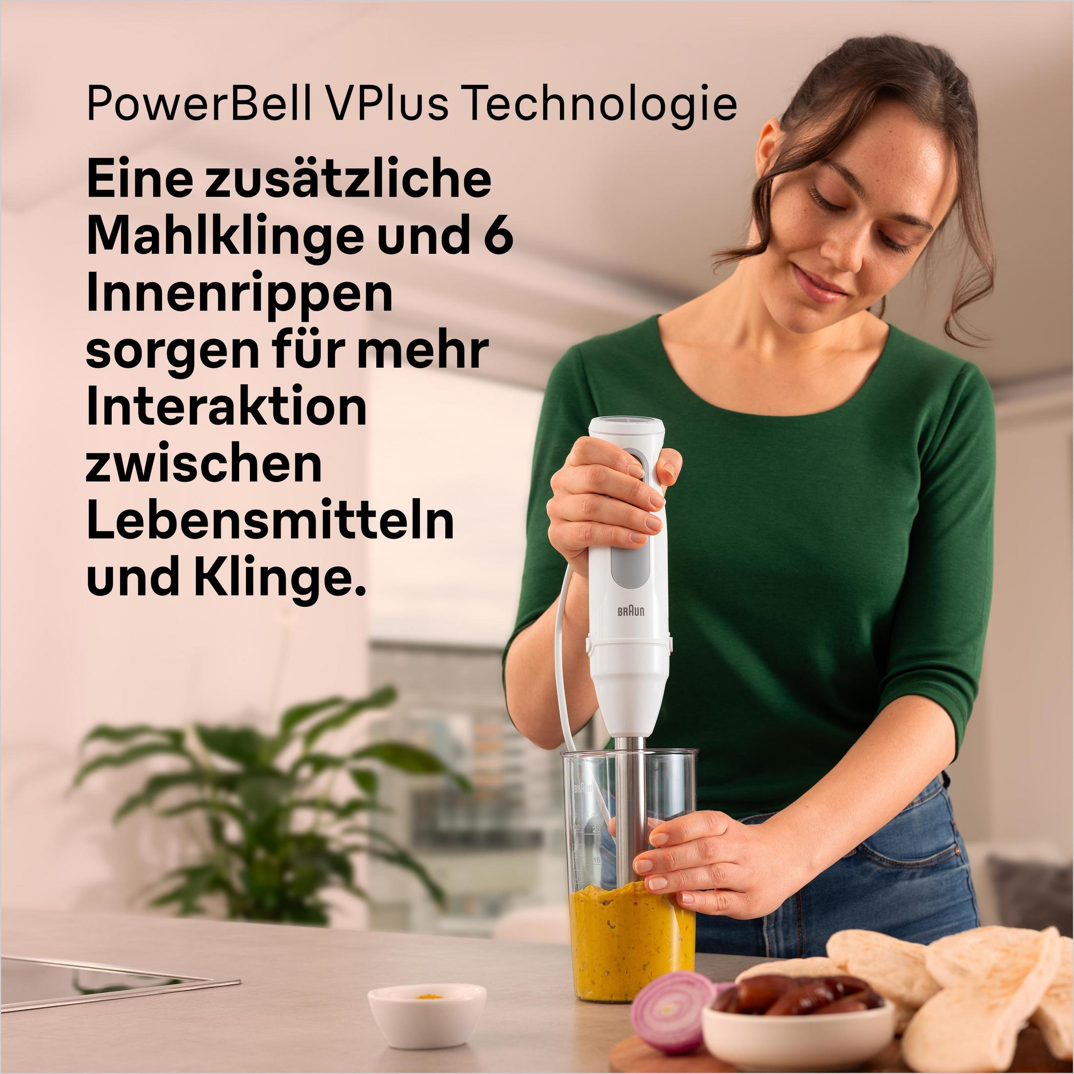 Kobieta miksuje żółte jedzenie w szklanym naczyniu blenderem.