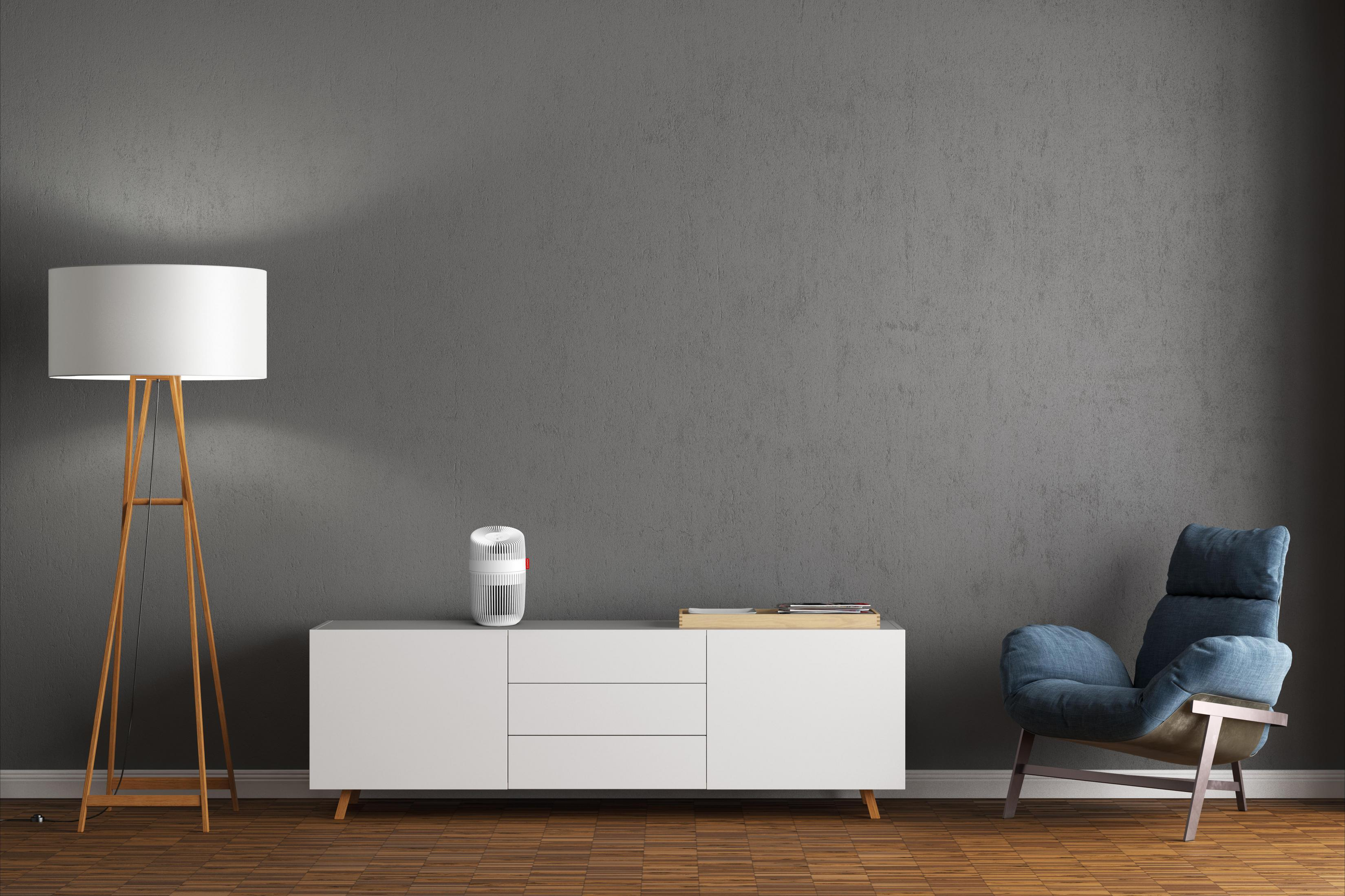 Una stanza moderna con credenza bianca, poltrona blu e lampada da terra.
