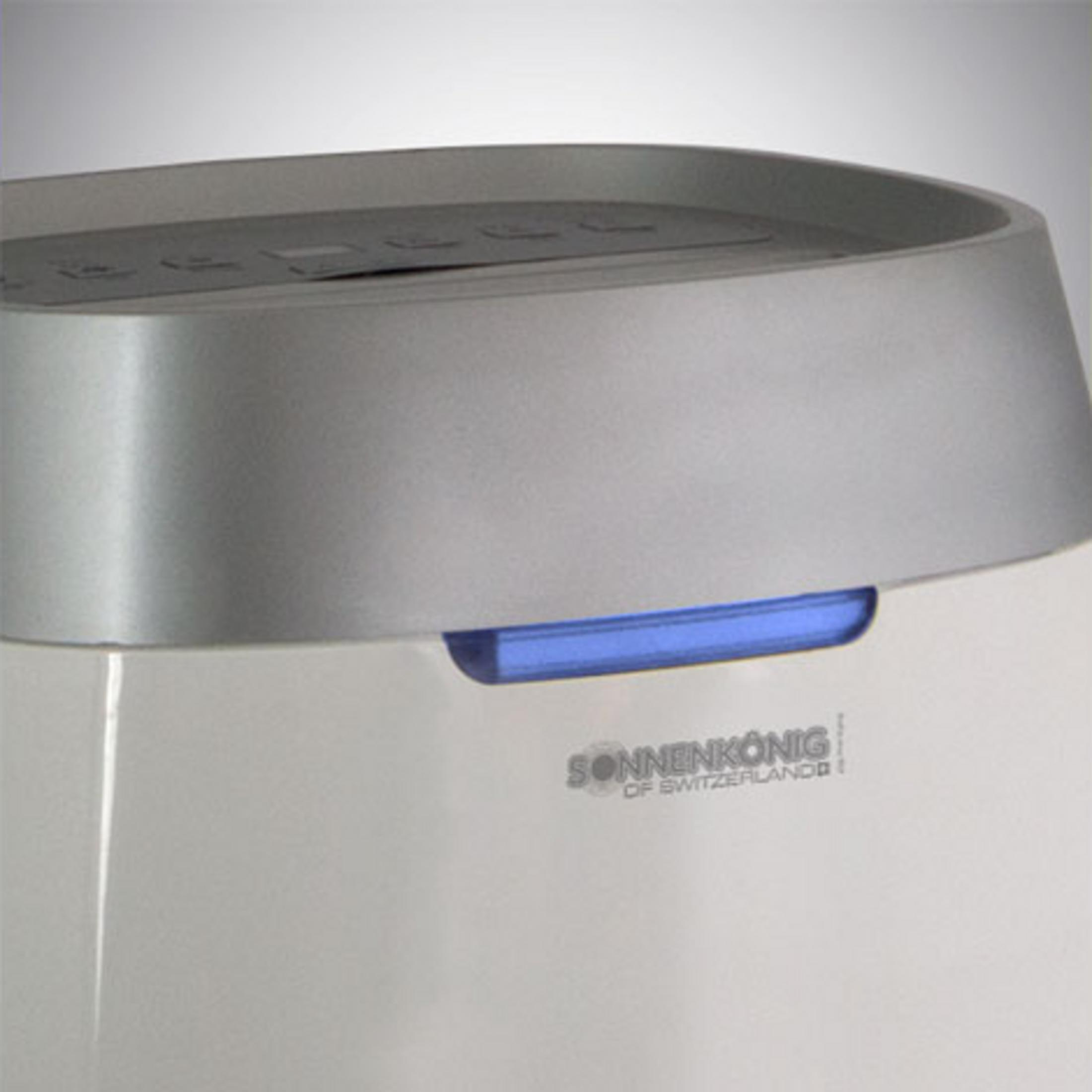 Un appareil blanc avec un bord argenté et une lumière bleue.