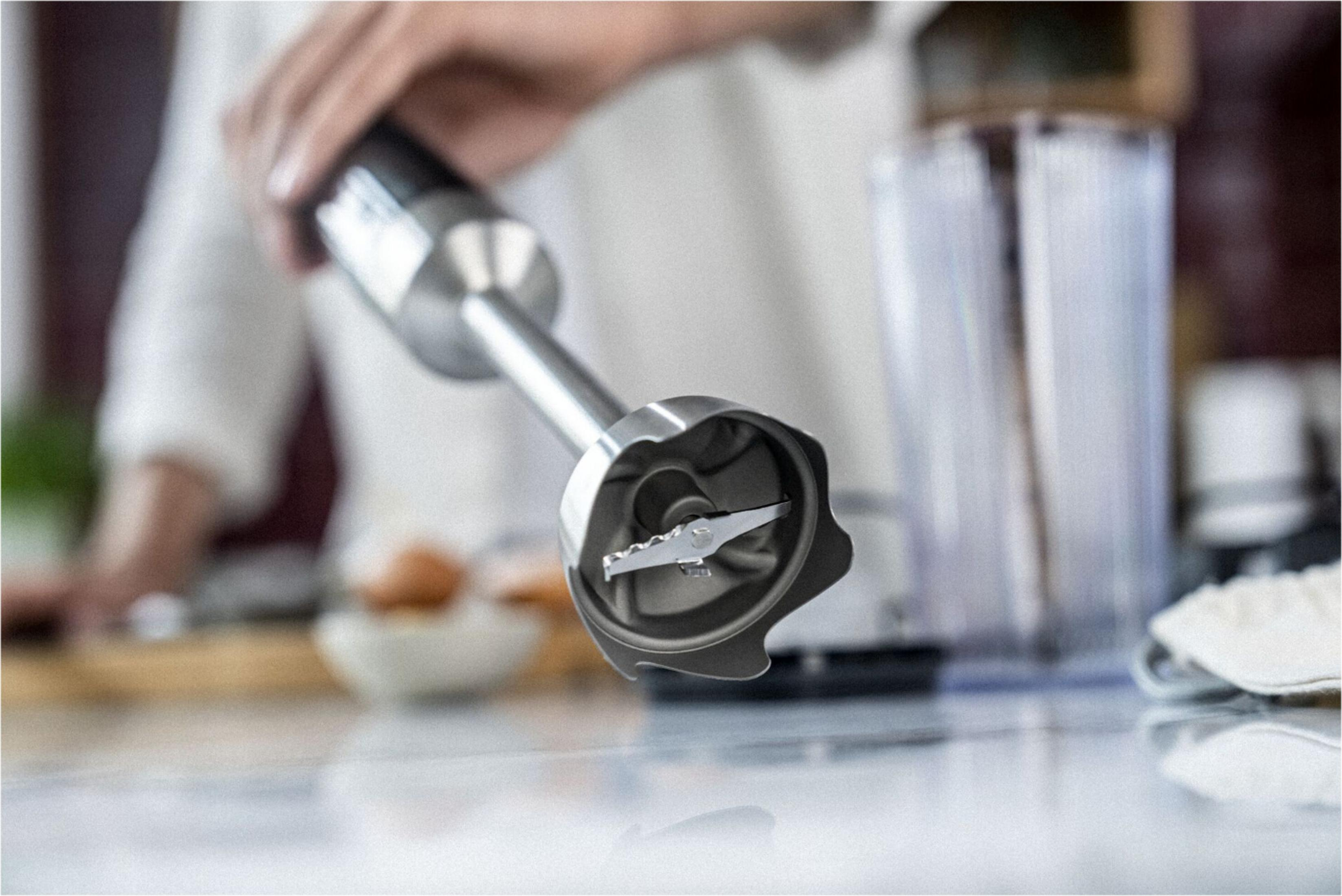 Zbliżenie blendera ręcznego z ostrzami, gotowego do miksowania.