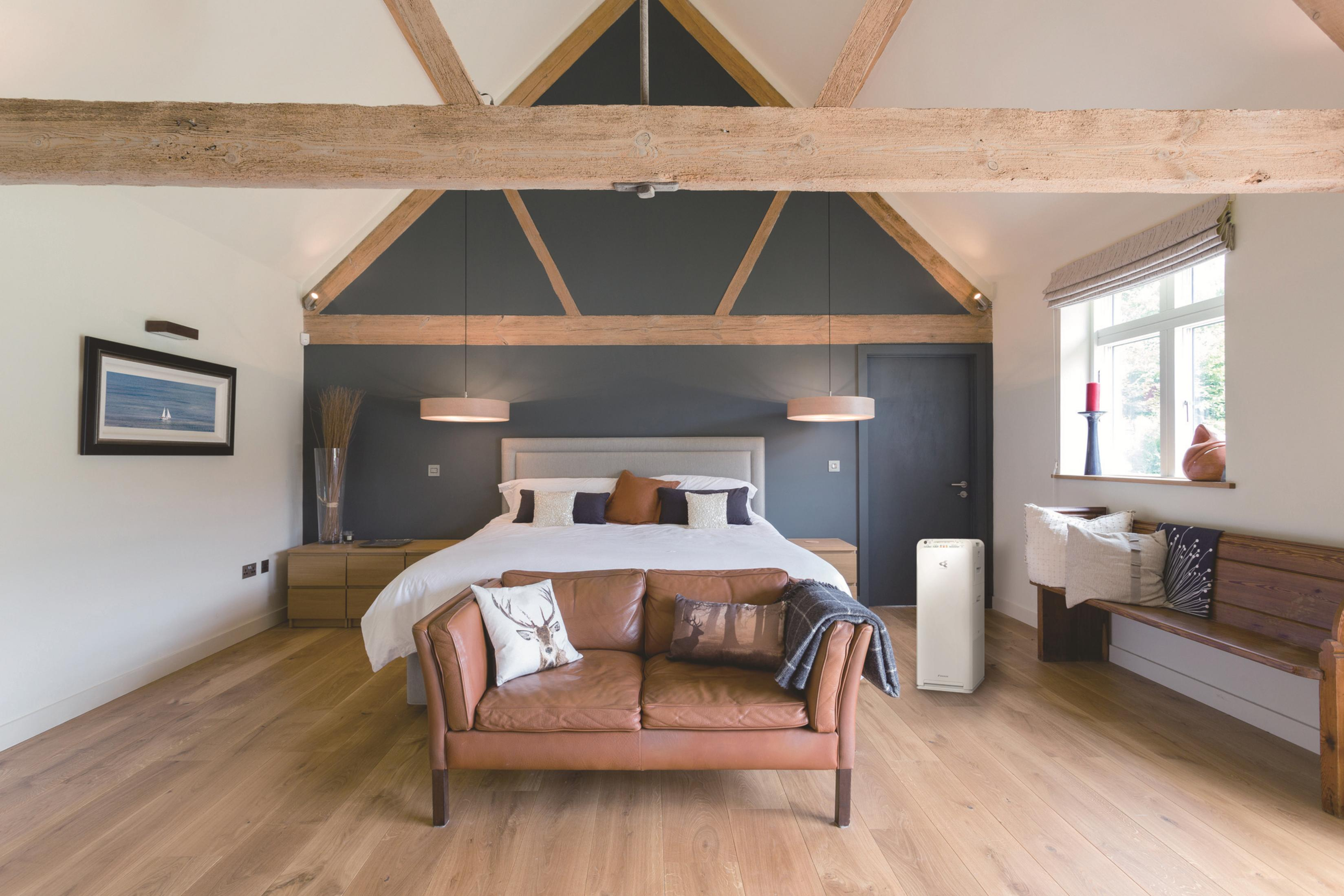Una camera da letto con travi in legno, divano in pelle marrone e letto.