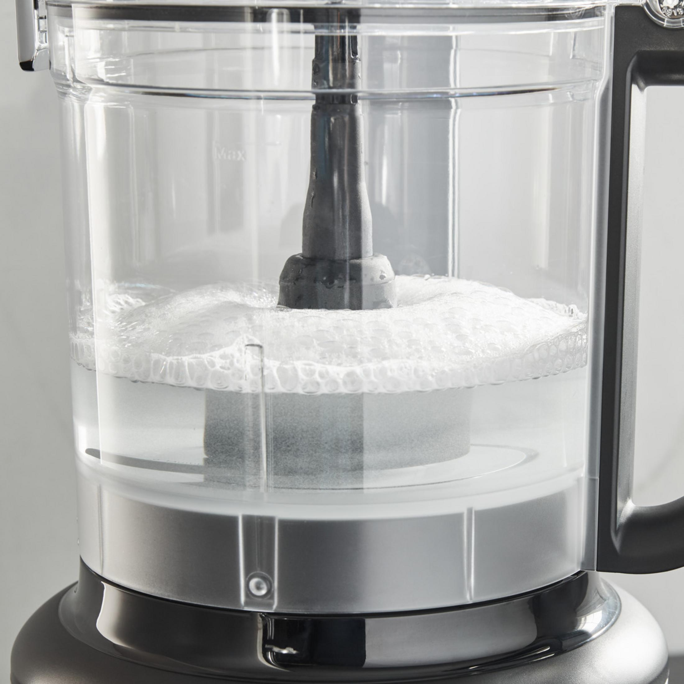 Una ciotola per robot da cucina con acqua e schiuma attorno a una frusta.