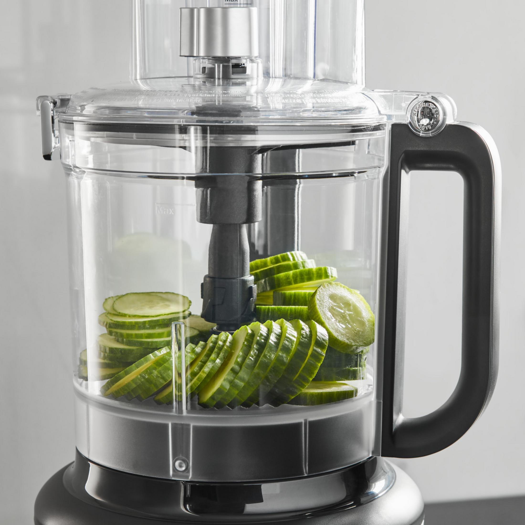 Una ciotola per robot da cucina con cetrioli affettati all'interno.