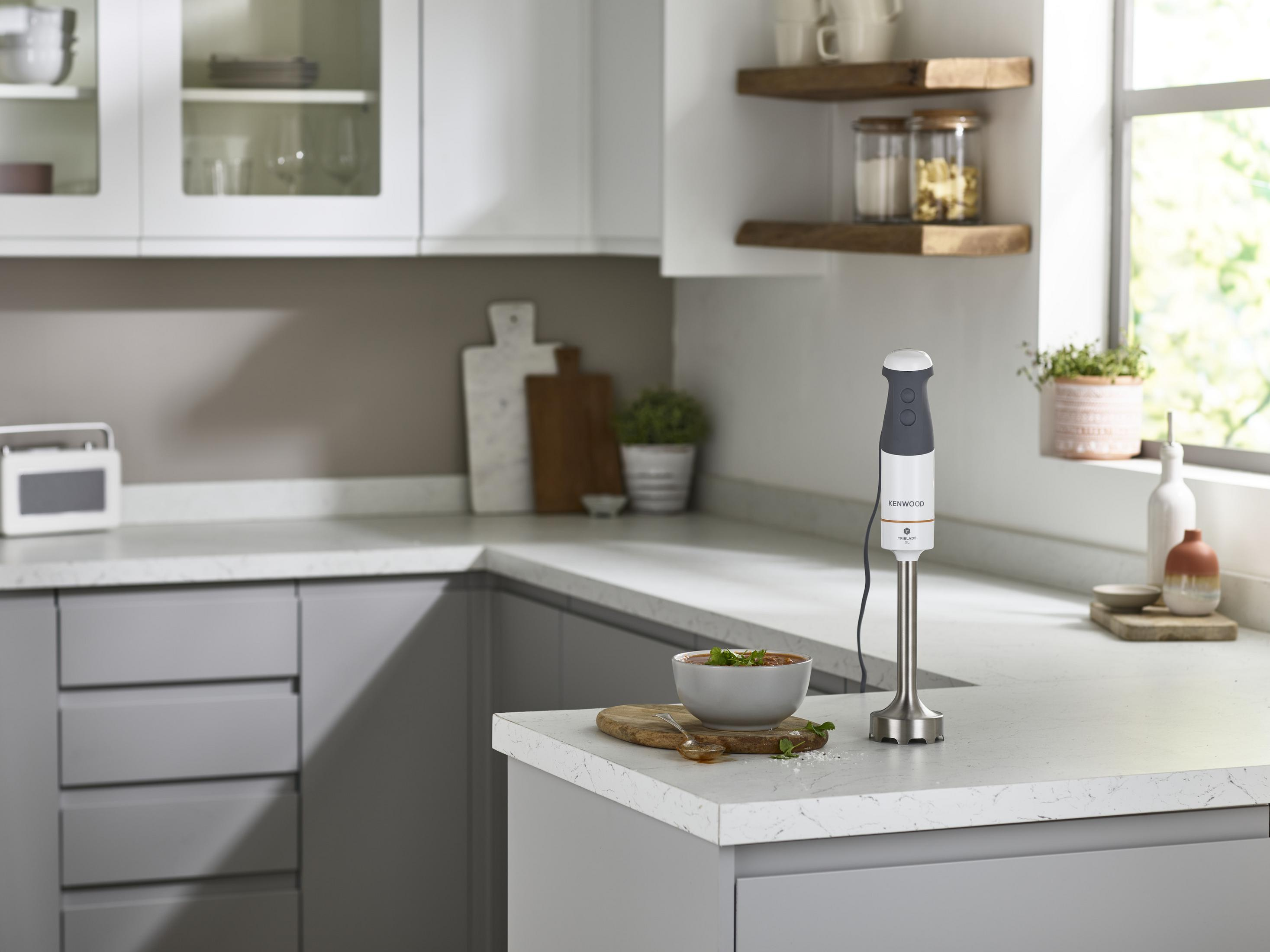 Blender ręczny stoi obok miski z zupą na blacie kuchennym.