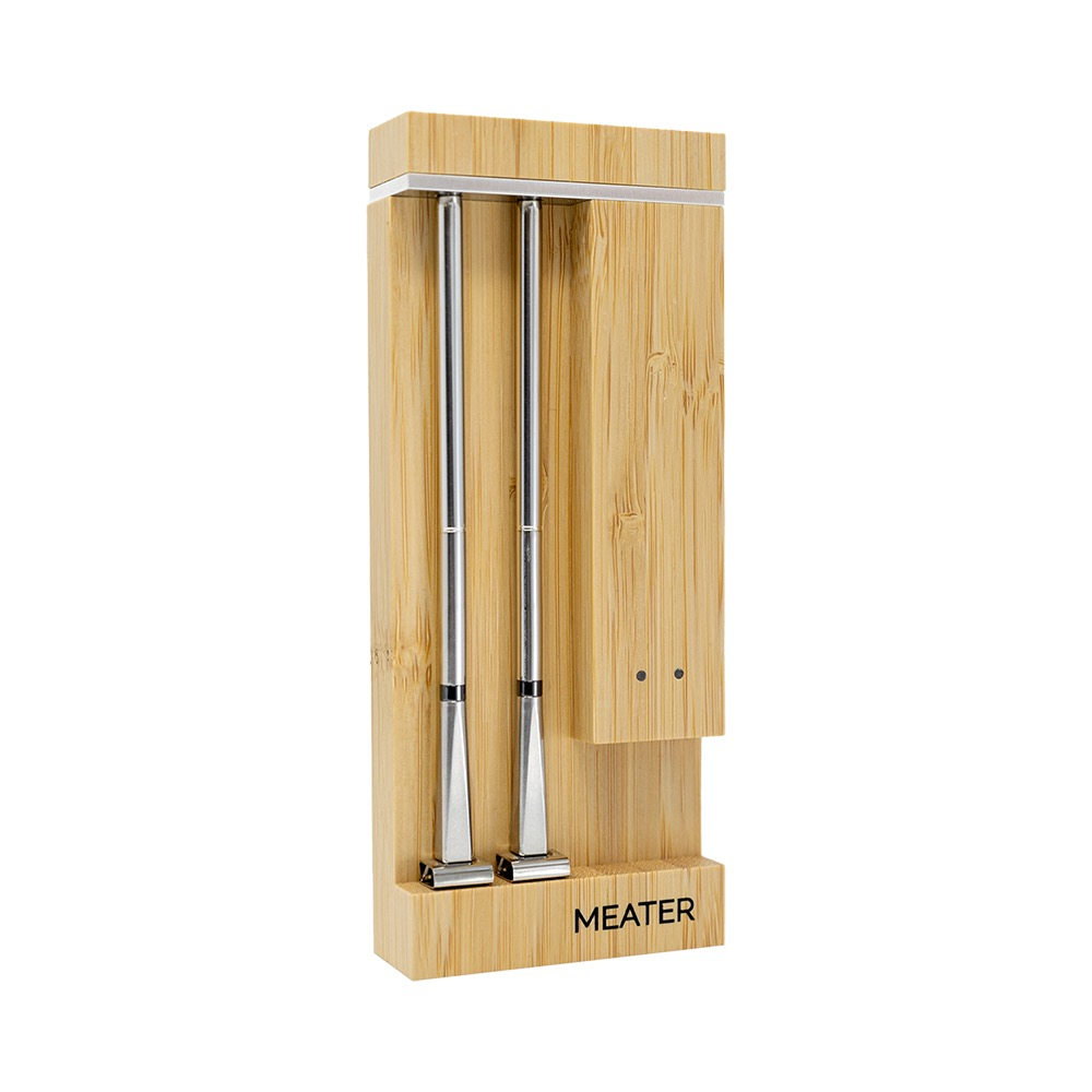 Un support en bois tenant deux fines sondes métalliques, avec le logo MEATER.