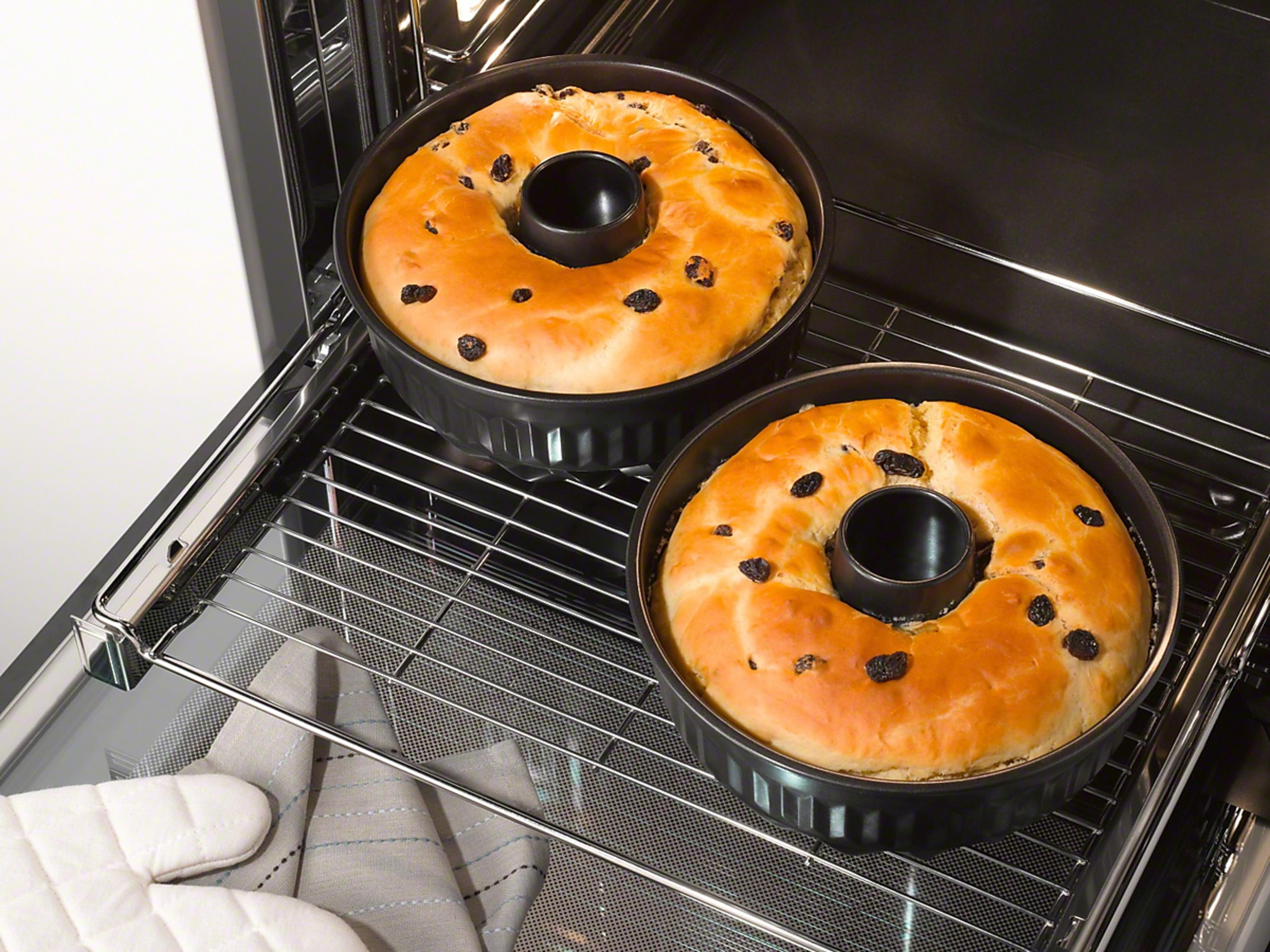 Zwei runde Kuchen mit Rosinen in Backformen im Ofen.