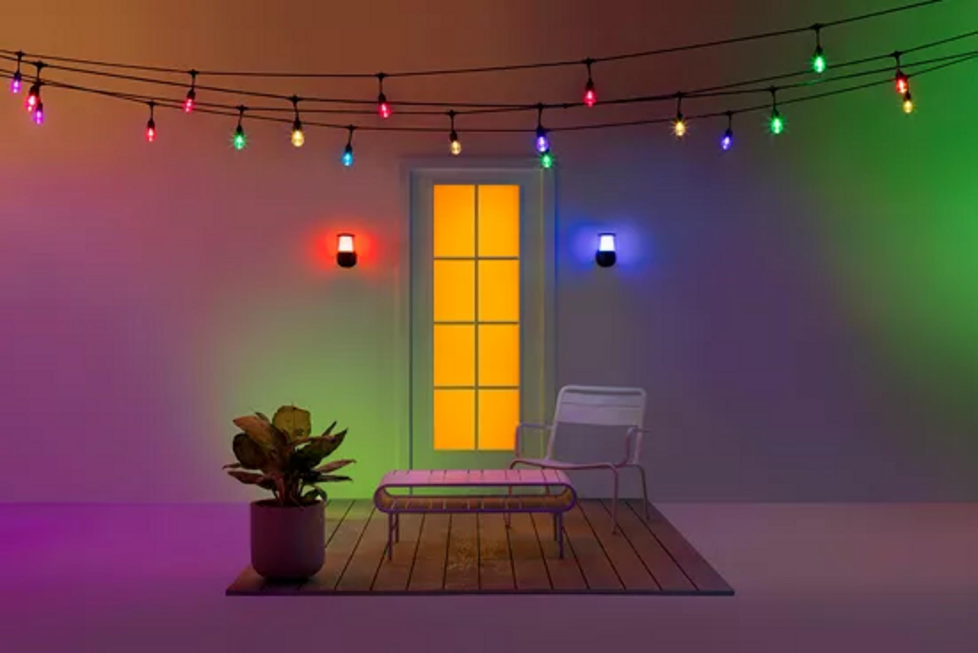 Bunte Lichterketten über einem Hof mit Pflanze, Tisch und Stuhl.