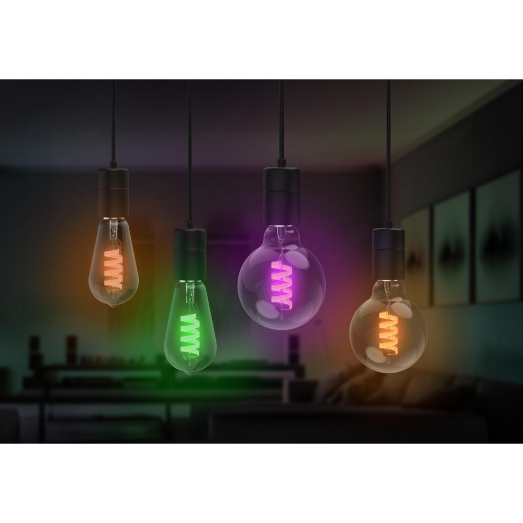 Quattro lampadine appese emettono luce arancione, verde, viola e gialla.