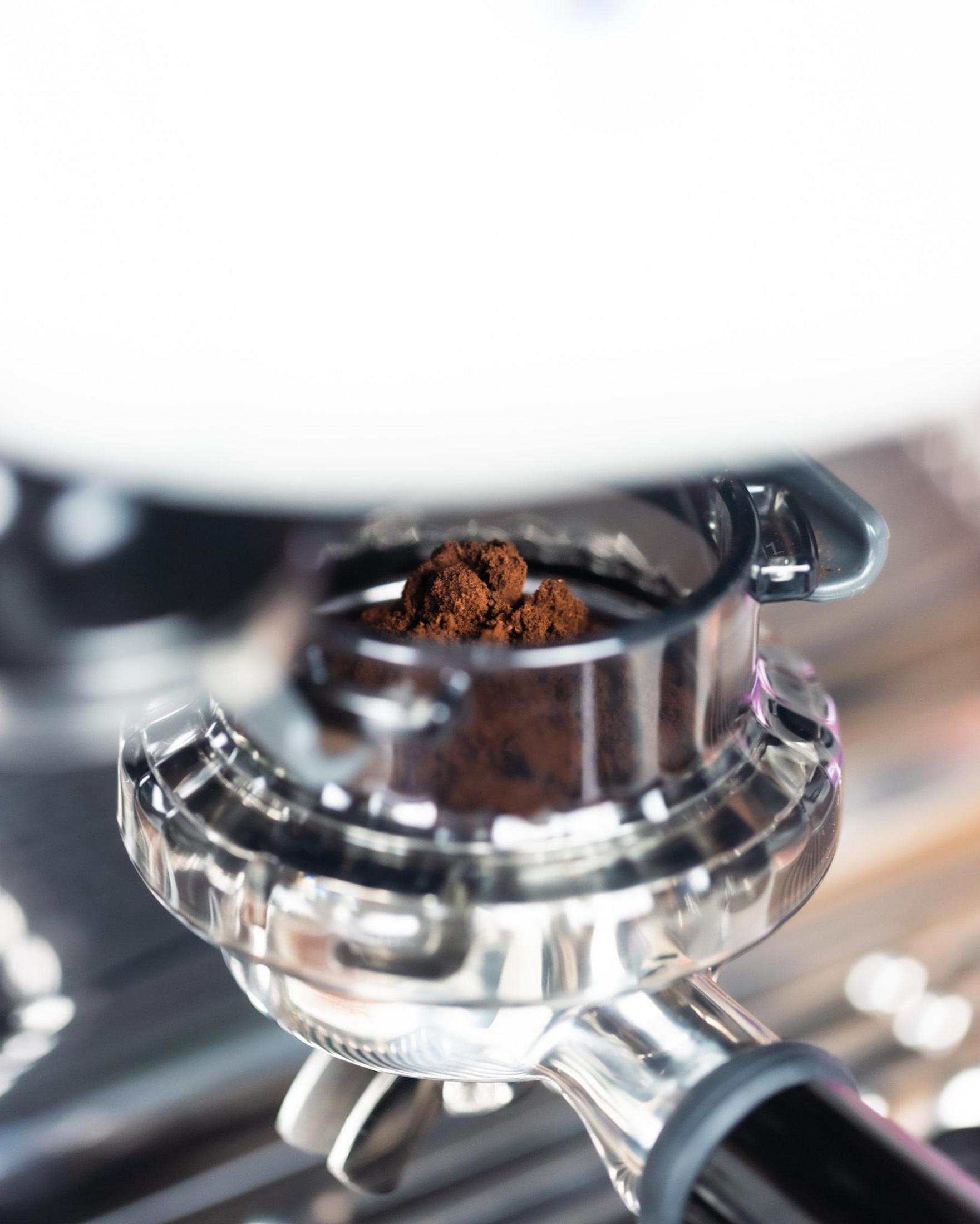 Gros plan de marc de café dans un porte-filtre métallique brillant d'une machine à expresso.