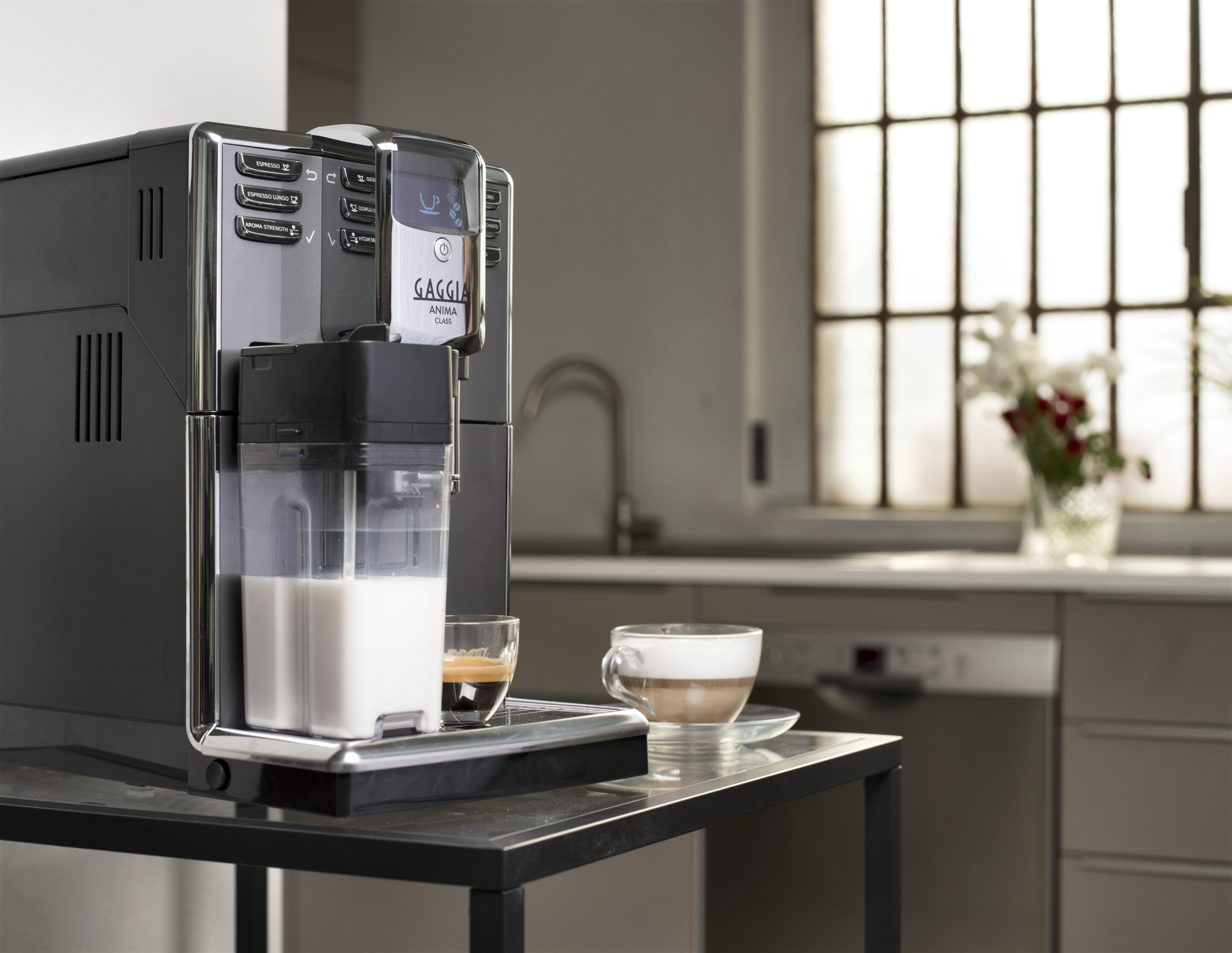 Ekspres do kawy Gaggia Anima Class z dzbankiem na mleko i filiżankami na stole.