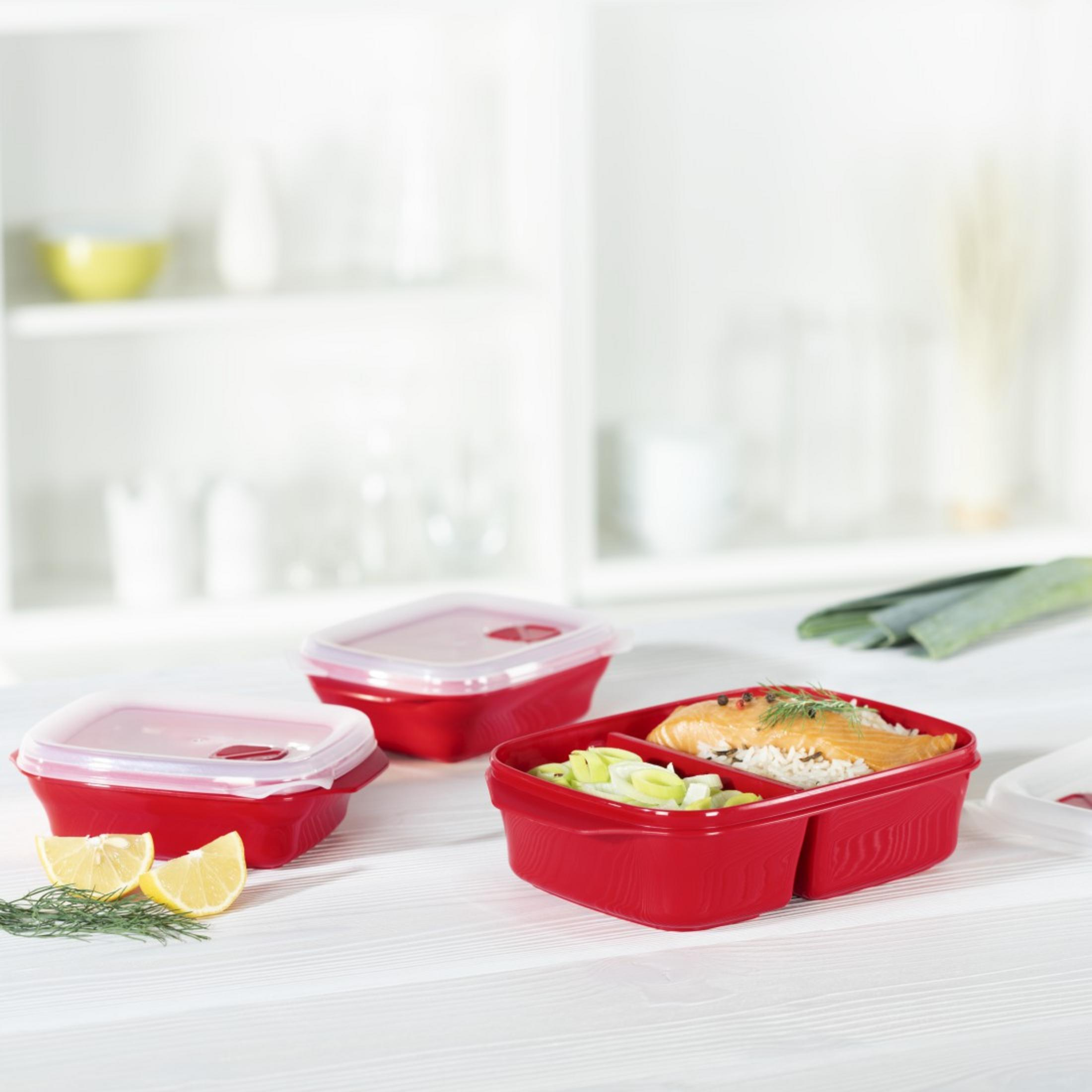 Rote Lunchboxen mit Deckeln, gefüllt mit Reis, Lachs, Lauch und Zitrone.
