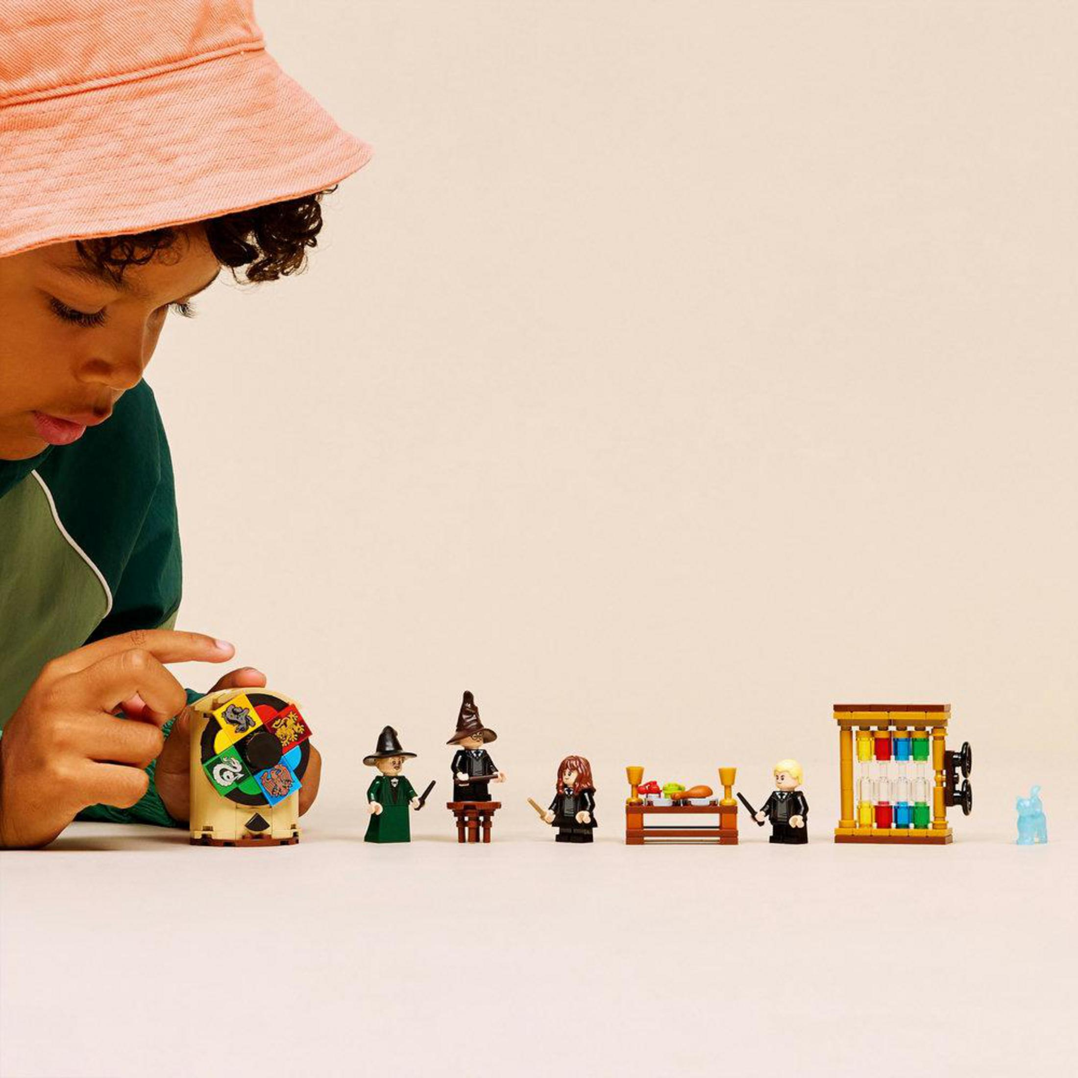 Turuncu şapkalı bir çocuk Lego figürleri ve dönen bir tekerlekle oynuyor.