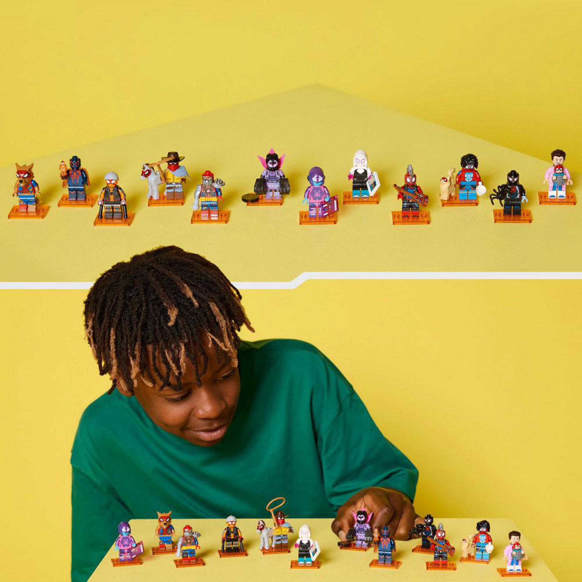 Un ragazzo guarda una fila di minifigure di supereroi su un tavolo.