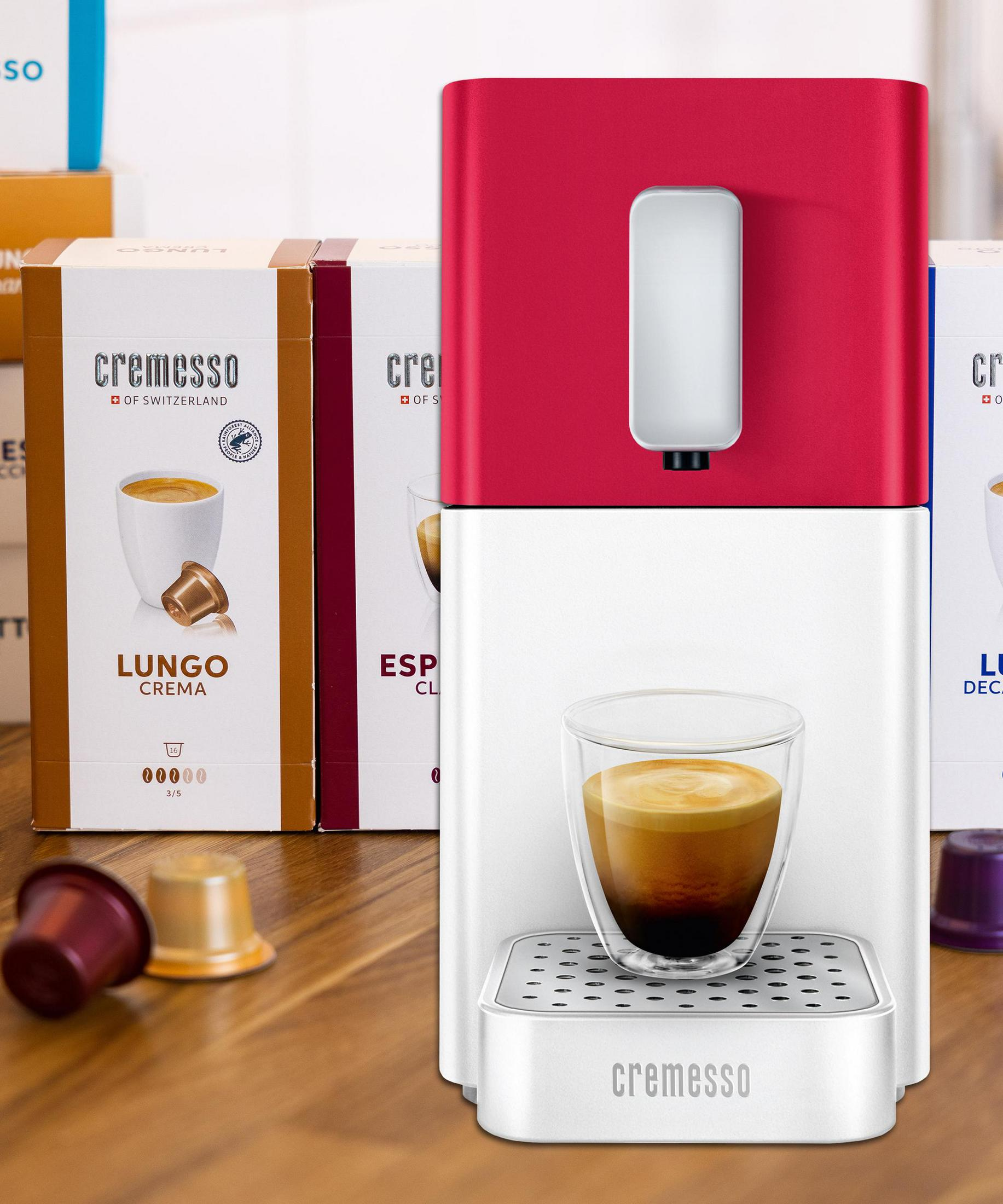 Eine rote und weiße Kaffeemaschine mit einer Tasse Espresso und Kapseln.