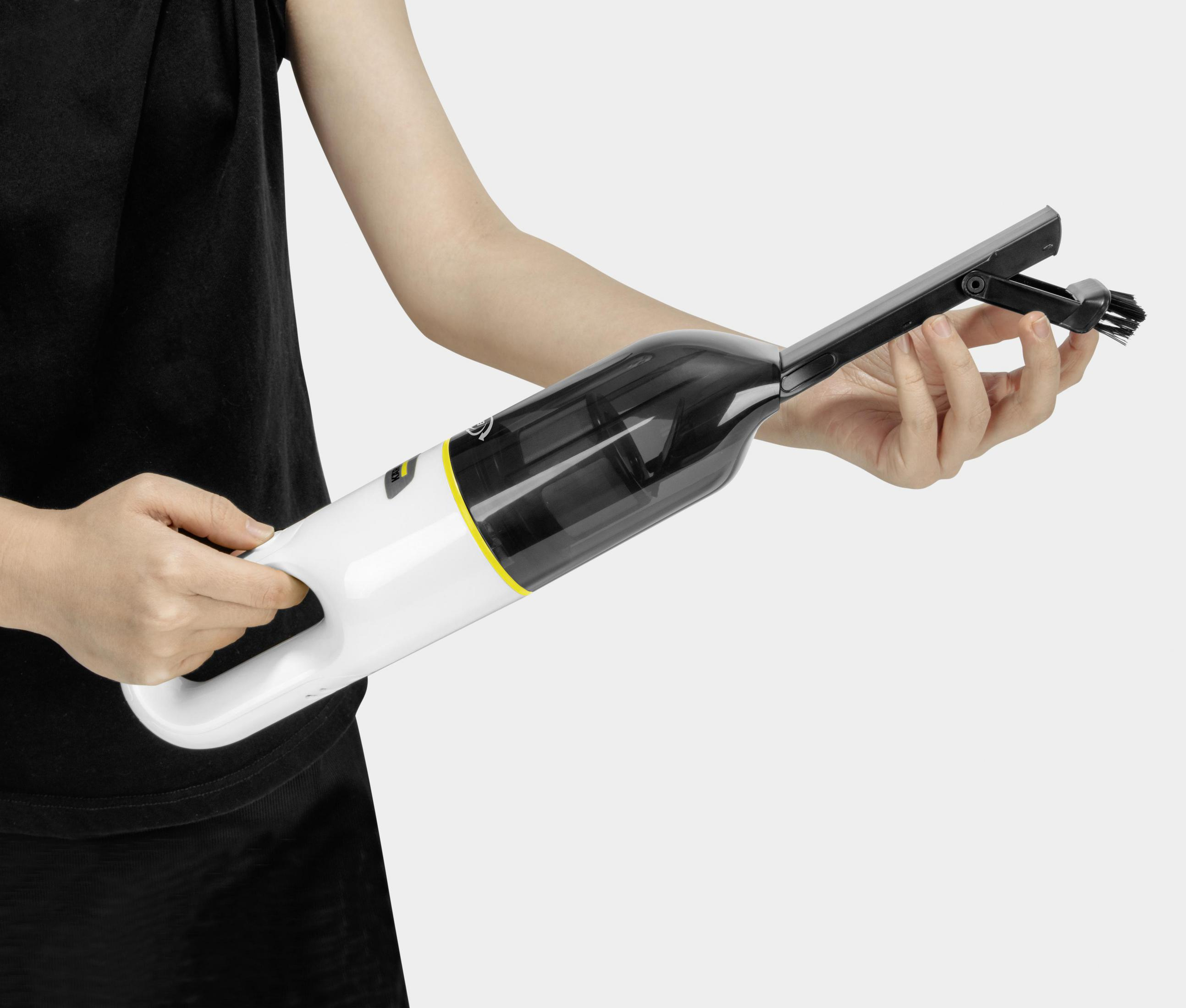 Persona che tiene un aspirapolvere bianco con contenitore nero e accento giallo.