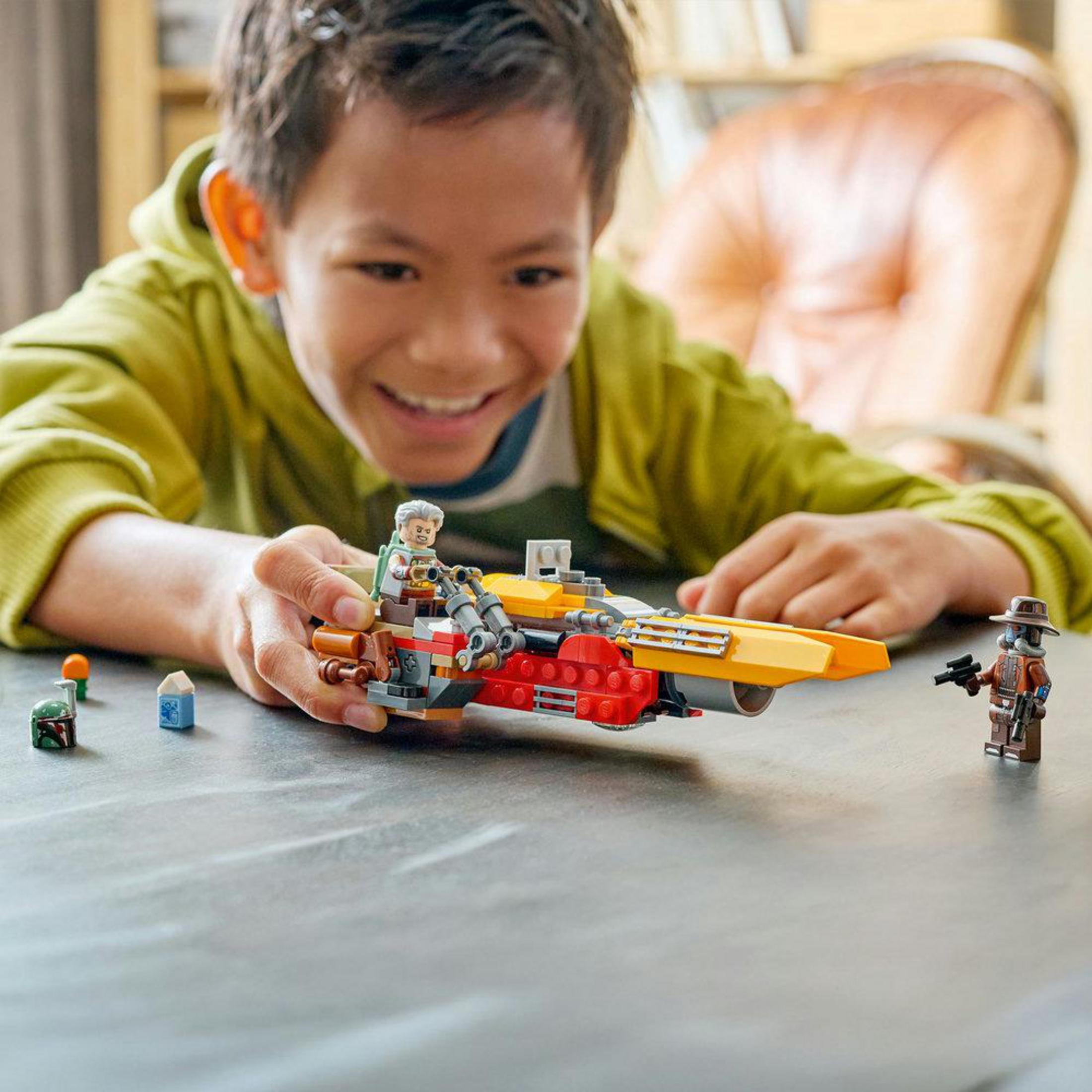 Bir çocuk masada Lego figürleri ve bir araçla oynuyor.