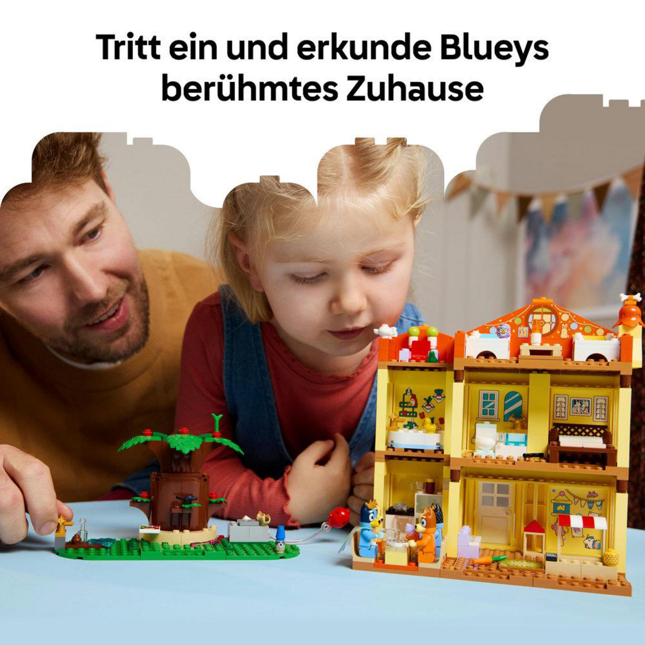 Adam ve çocuk, Bluey oyun evi ve ağacıyla oynuyor.