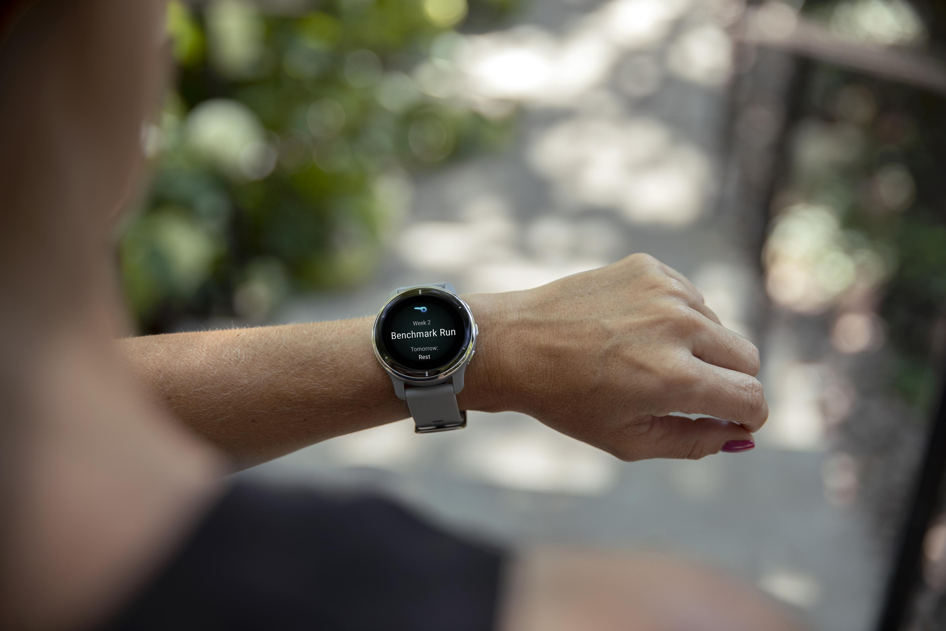 Eine graue Smartwatch am Handgelenk zeigt „Benchmark Run“ und „Morgen: Ruhe“ an.