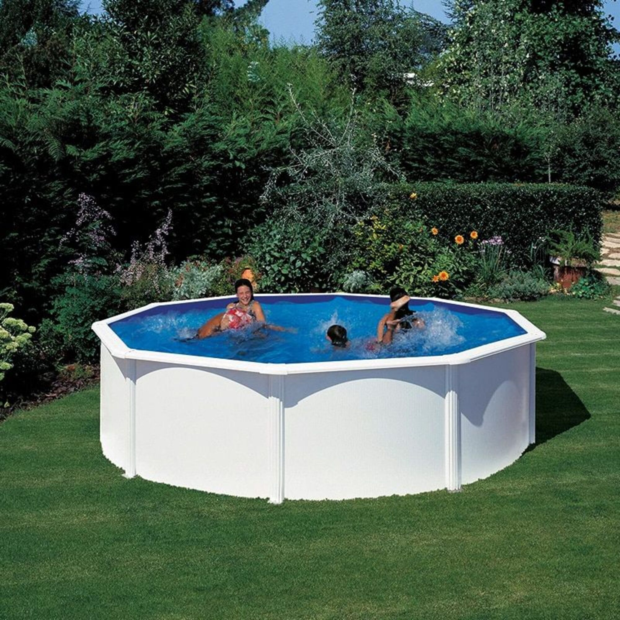 Una piscina blanca con agua azul donde tres personas chapotean en el jardín.
