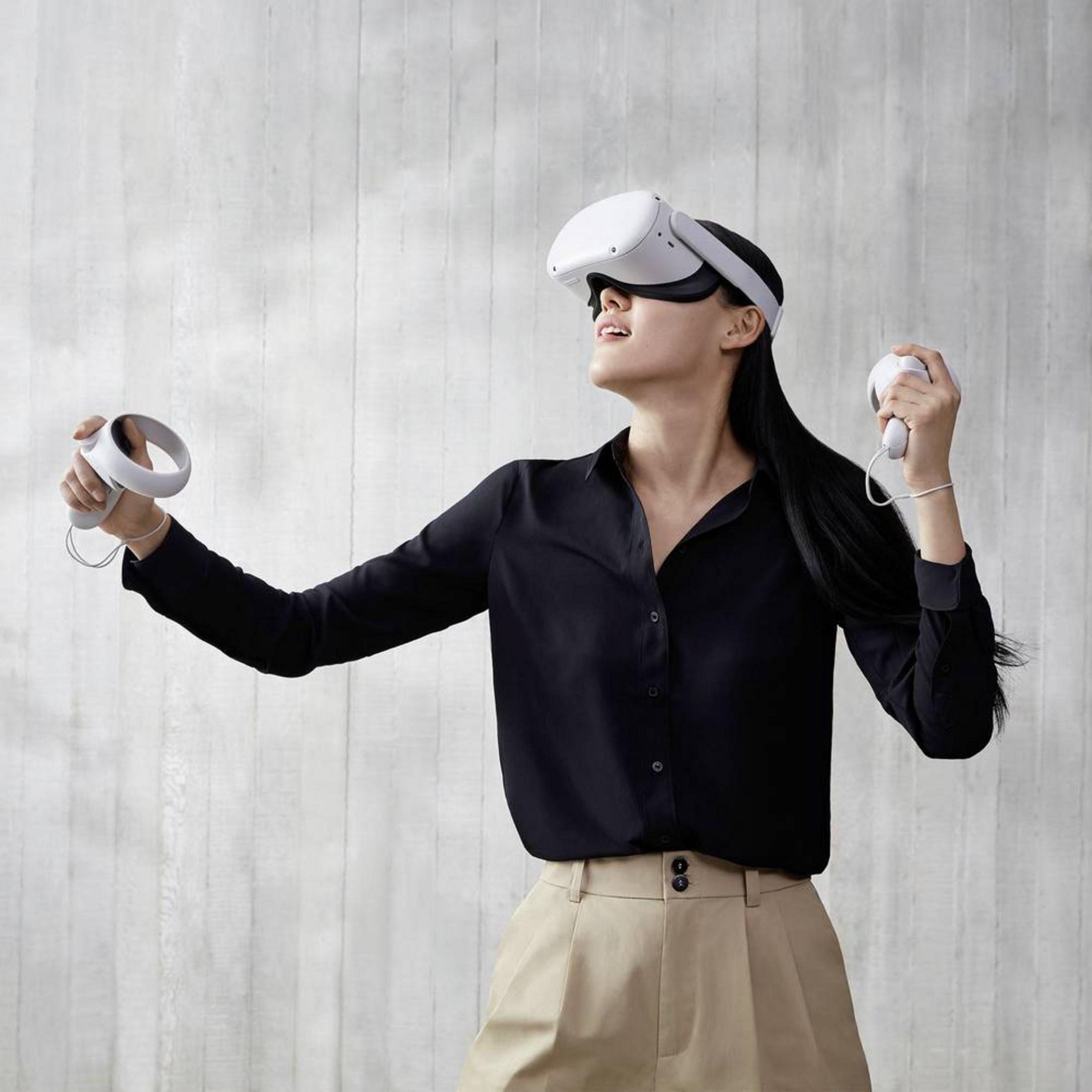 Frau in schwarzer Bluse und Khaki-Hose trägt VR-Headset und Controller.