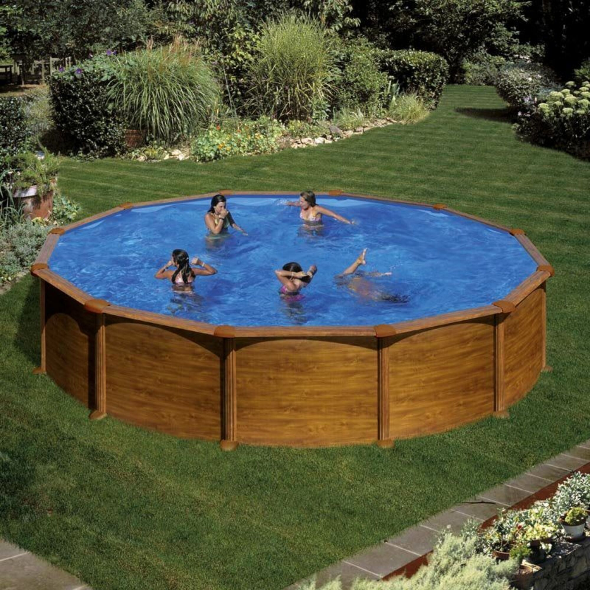 Cinco personas nadan en una piscina redonda con revestimiento de madera en un jardín verde.