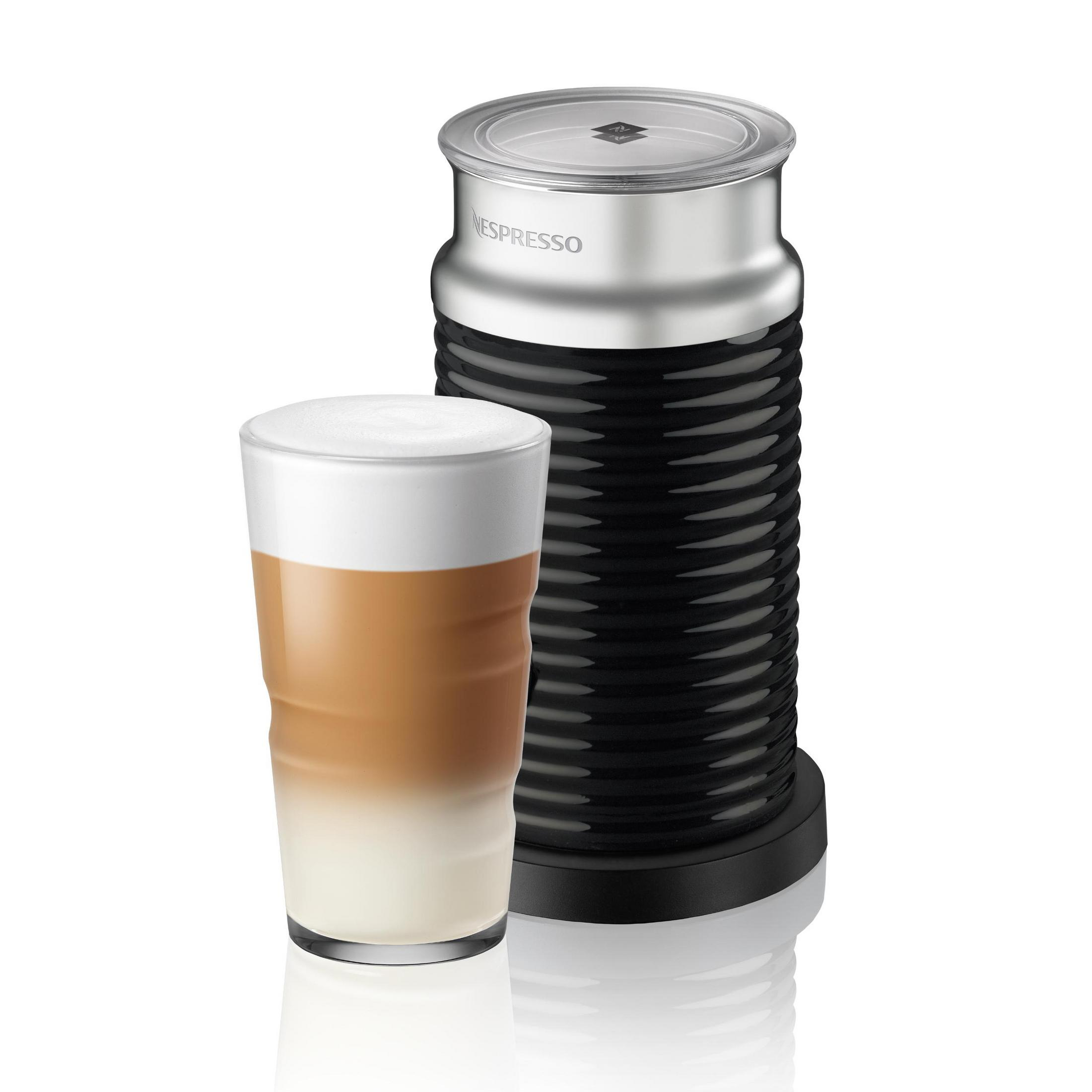 Ein Nespresso Milchaufschäumer steht neben einem Glas Latte Macchiato.