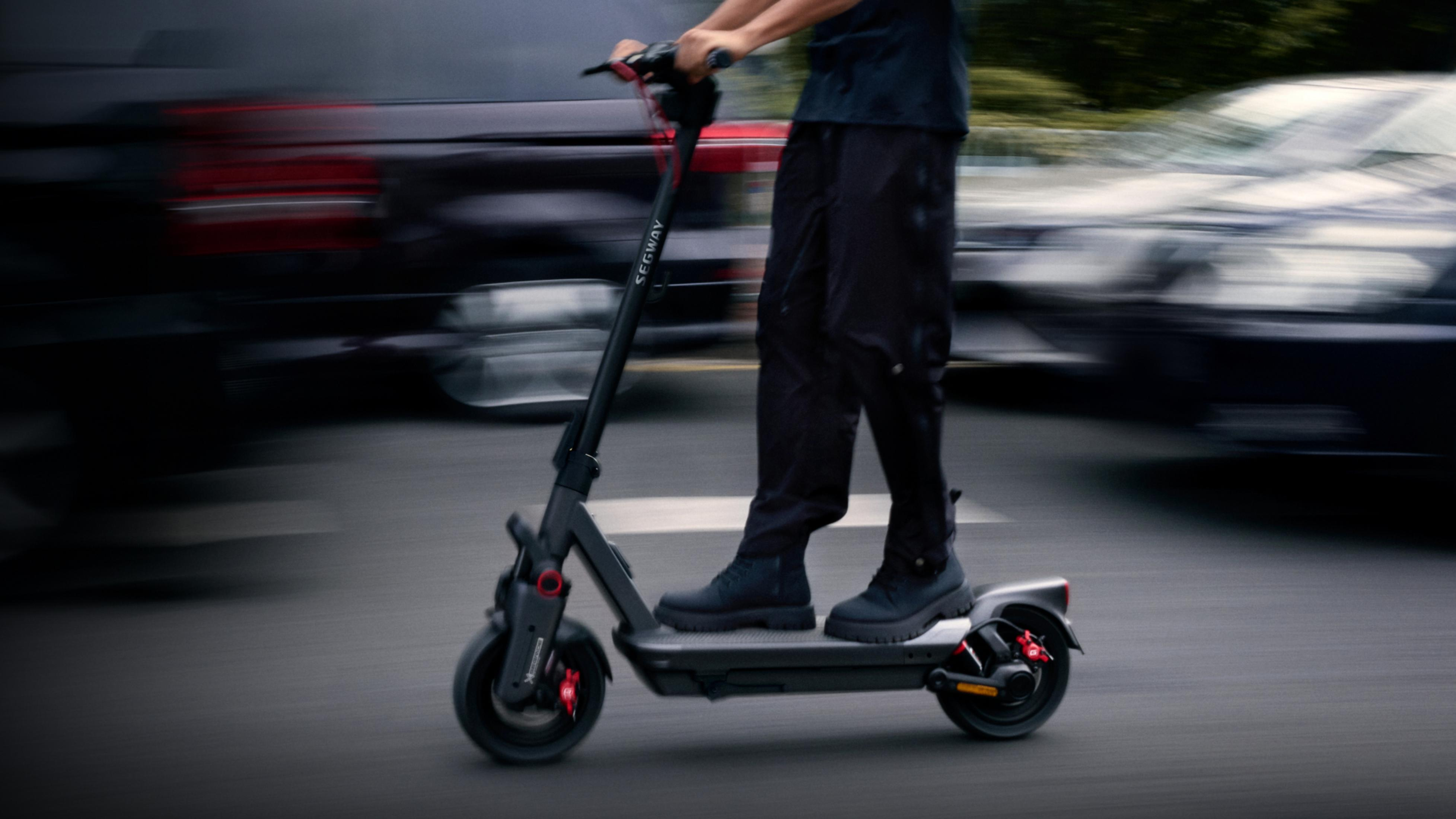 Persona in sella a uno scooter Segway con freni rossi, auto sullo sfondo.