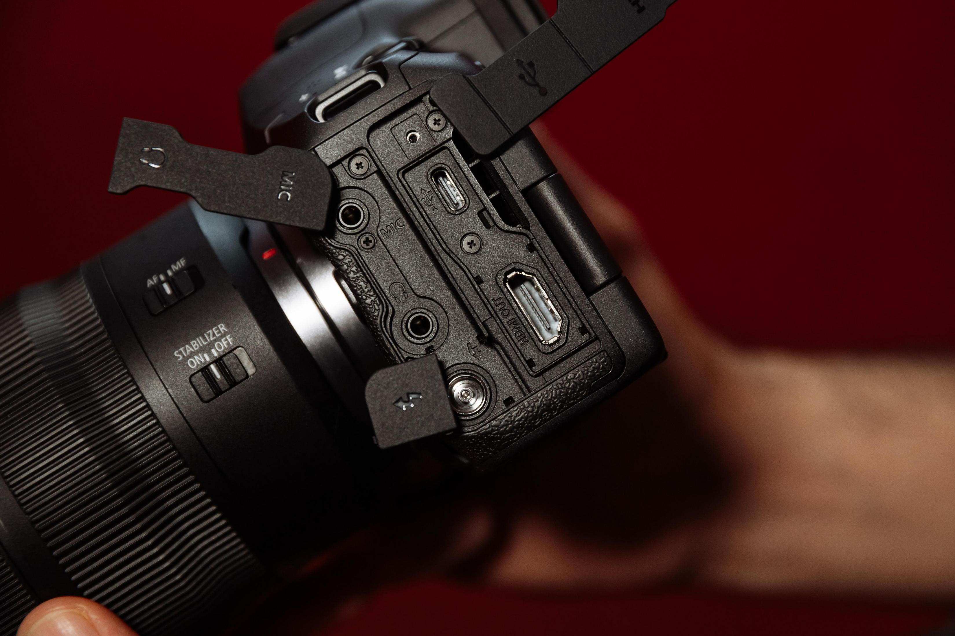 Zbliżenie na porty aparatu: USB, mikrofon i wyjście HDMI, na czerwonym tle.