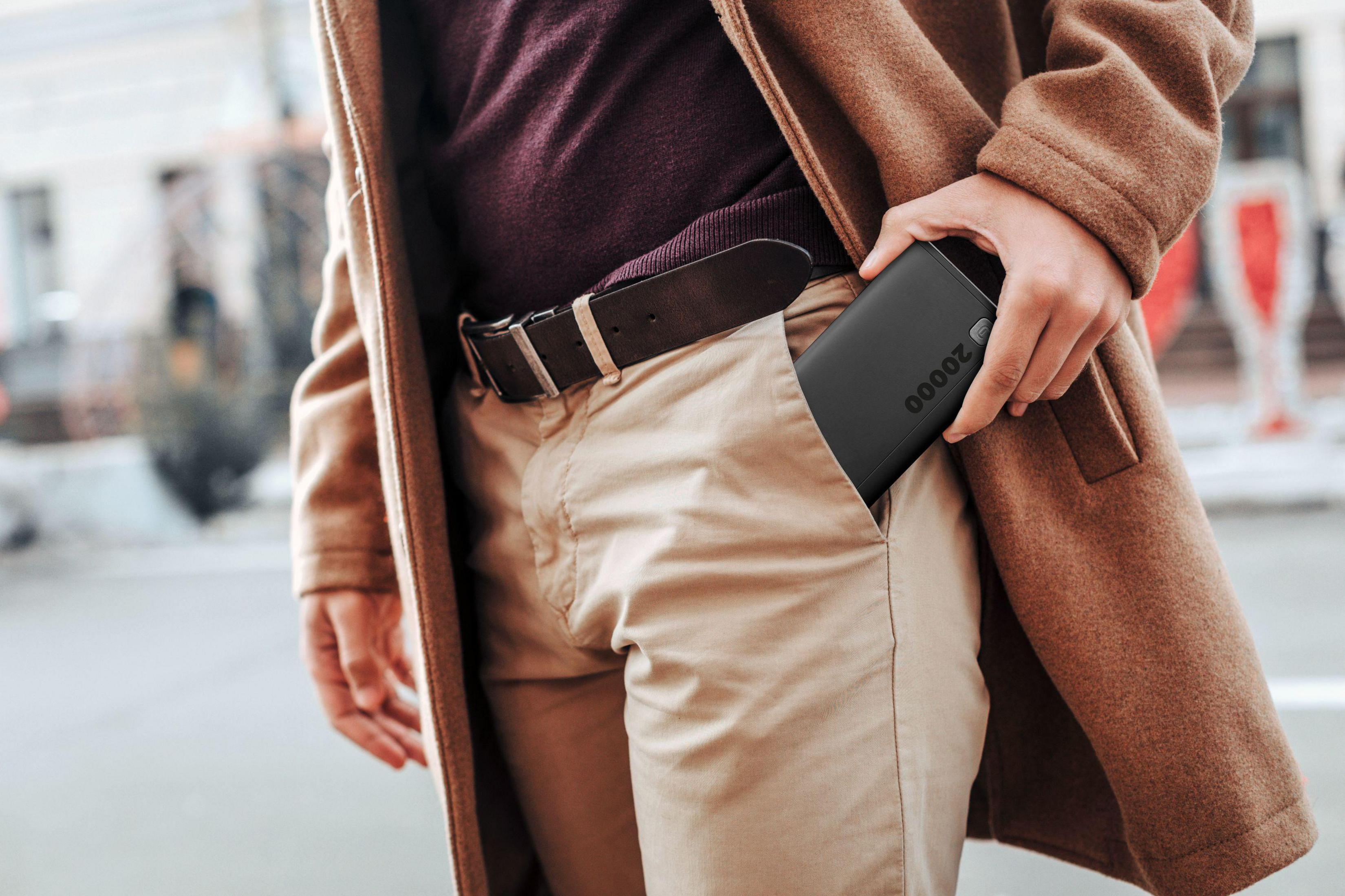 Mężczyzna wkłada czarny power bank z napisem "20000" do kieszeni.
