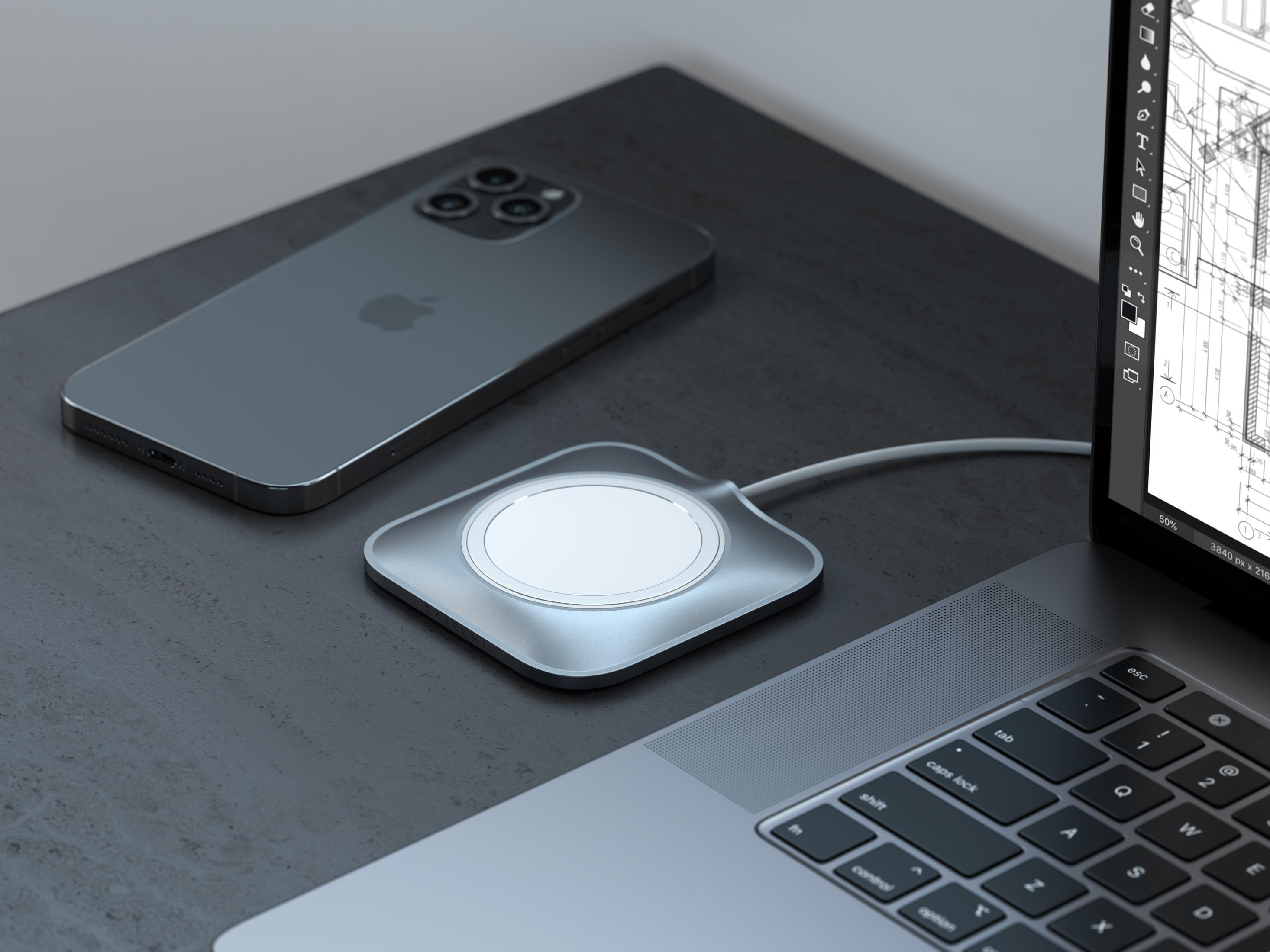 Ein silbernes iPhone liegt neben einem MagSafe-Ladegerät und einem Laptop.