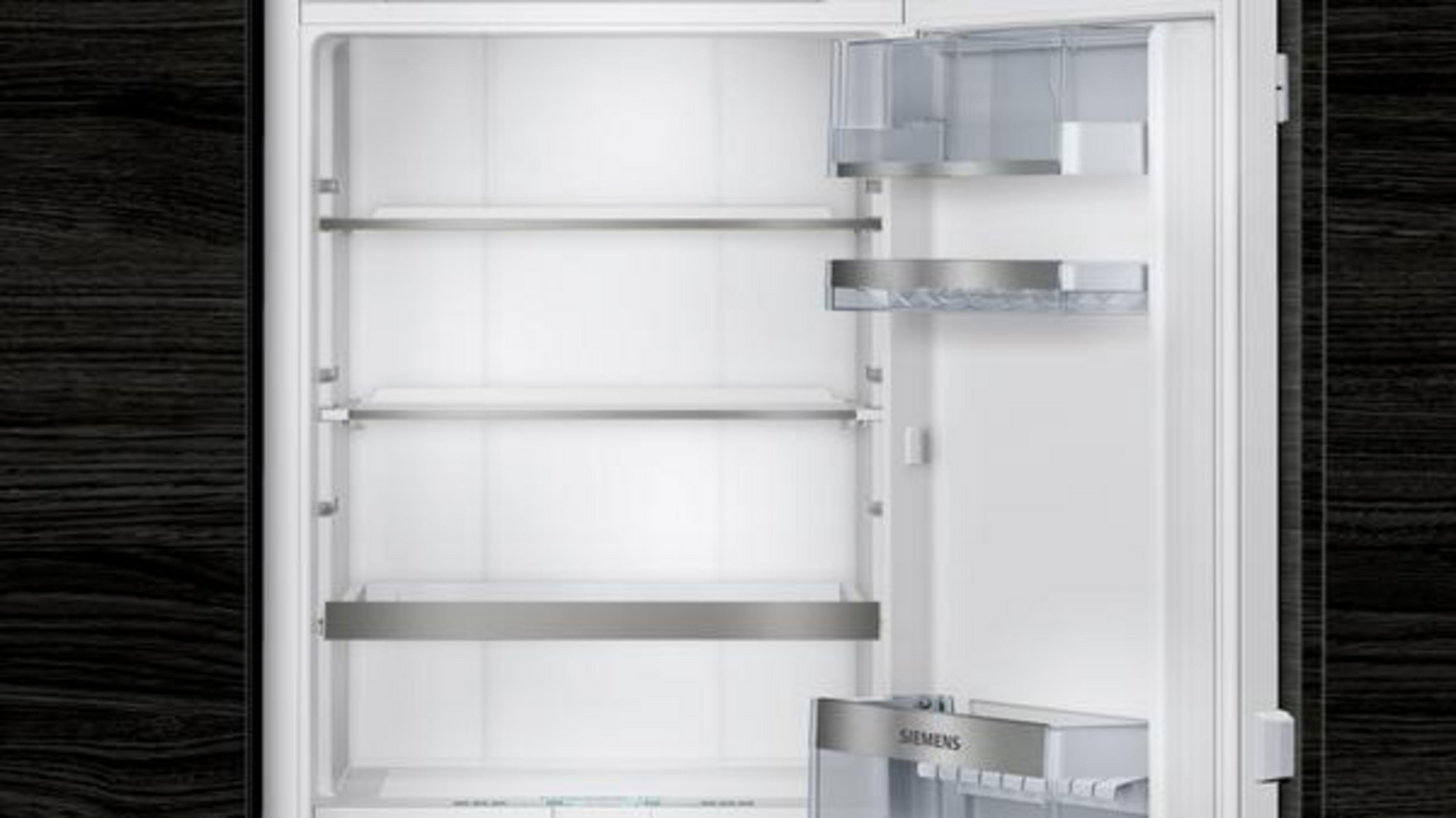 Ein leerer weier Kõhlschrank mit Glasablagen und Schubladen.