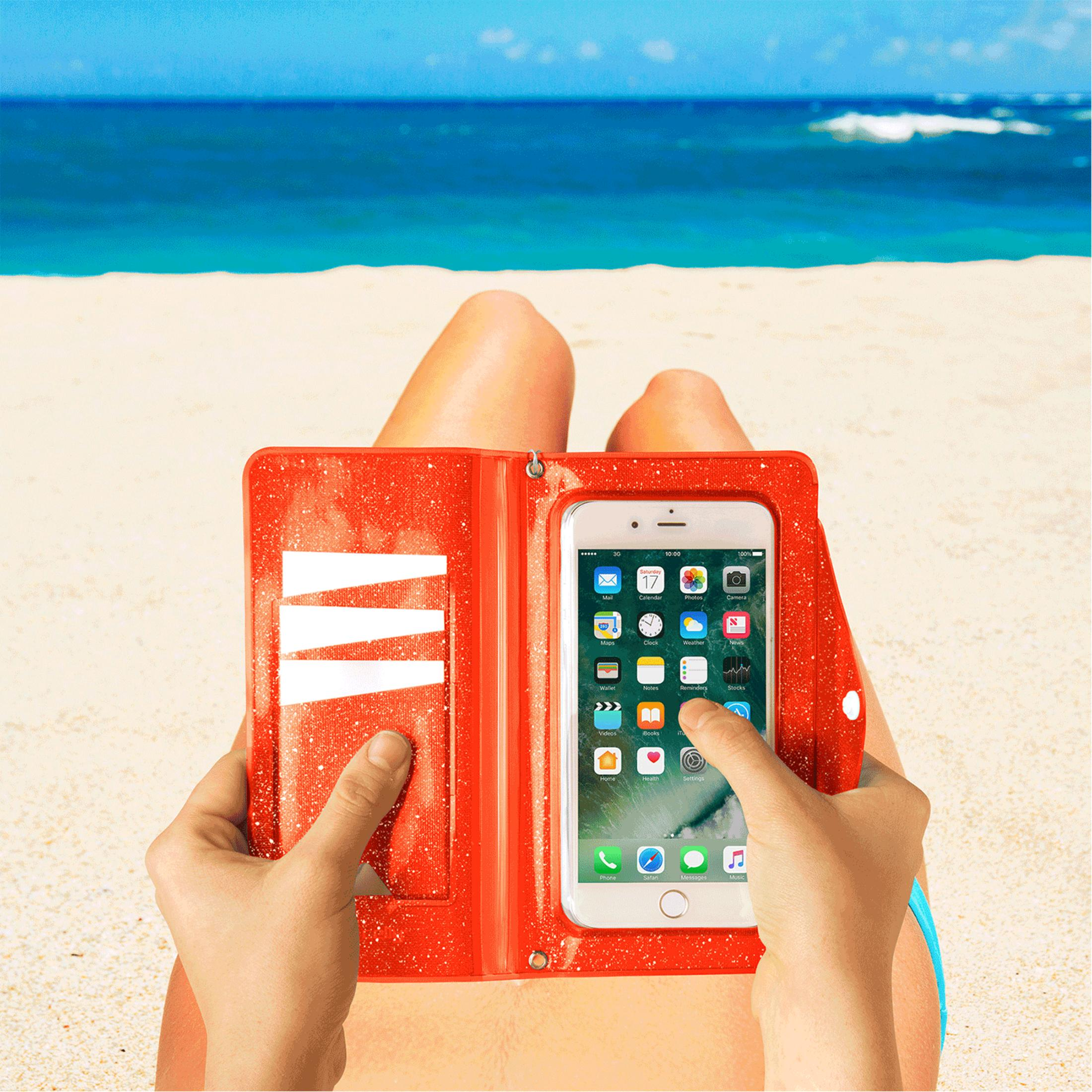 Persona tiene uno smartphone in una custodia rossa sulla spiaggia. Mare sullo sfondo.