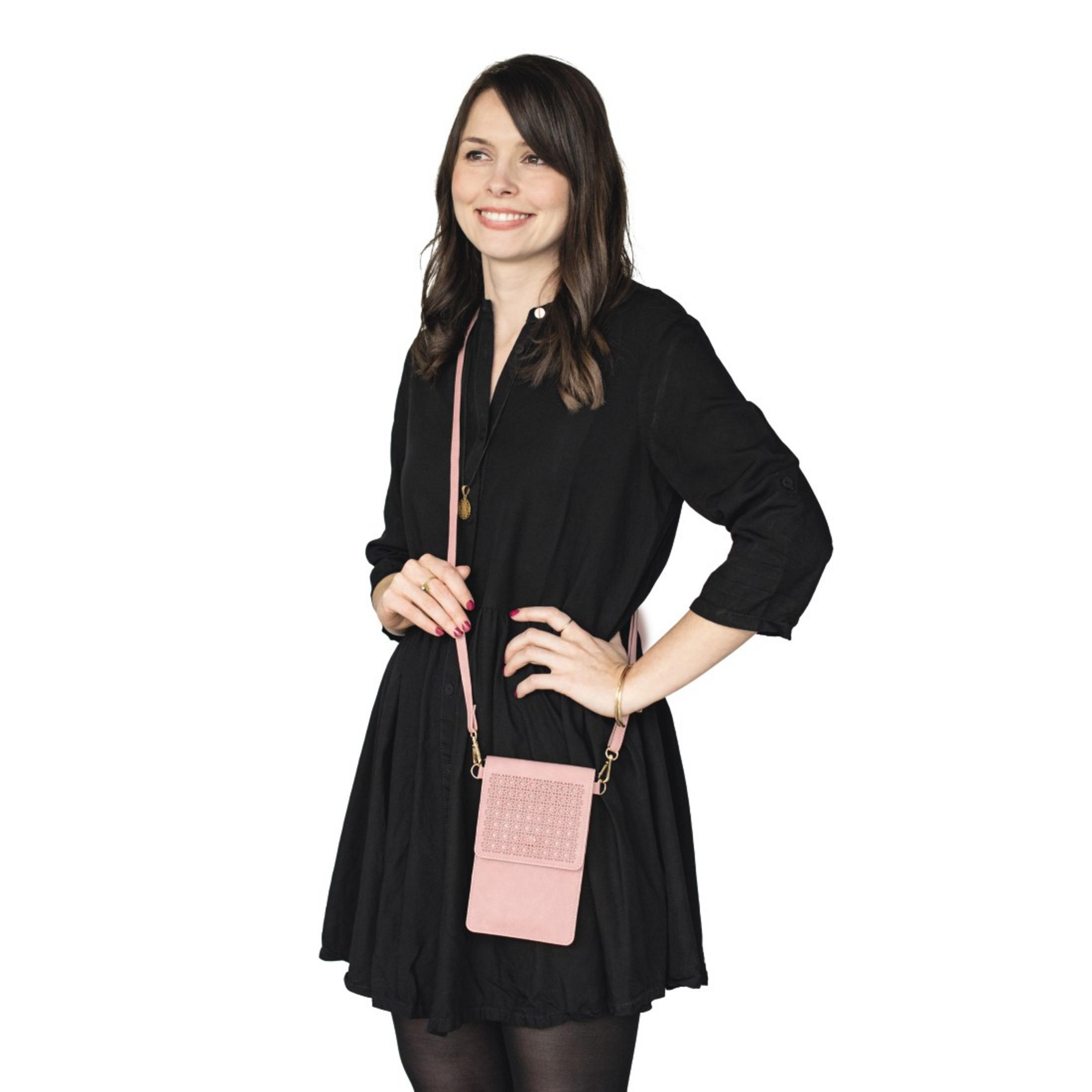 Frau in schwarzem Kleid mit rosa Umhängetasche, steht mit Händen in der Hüfte.
