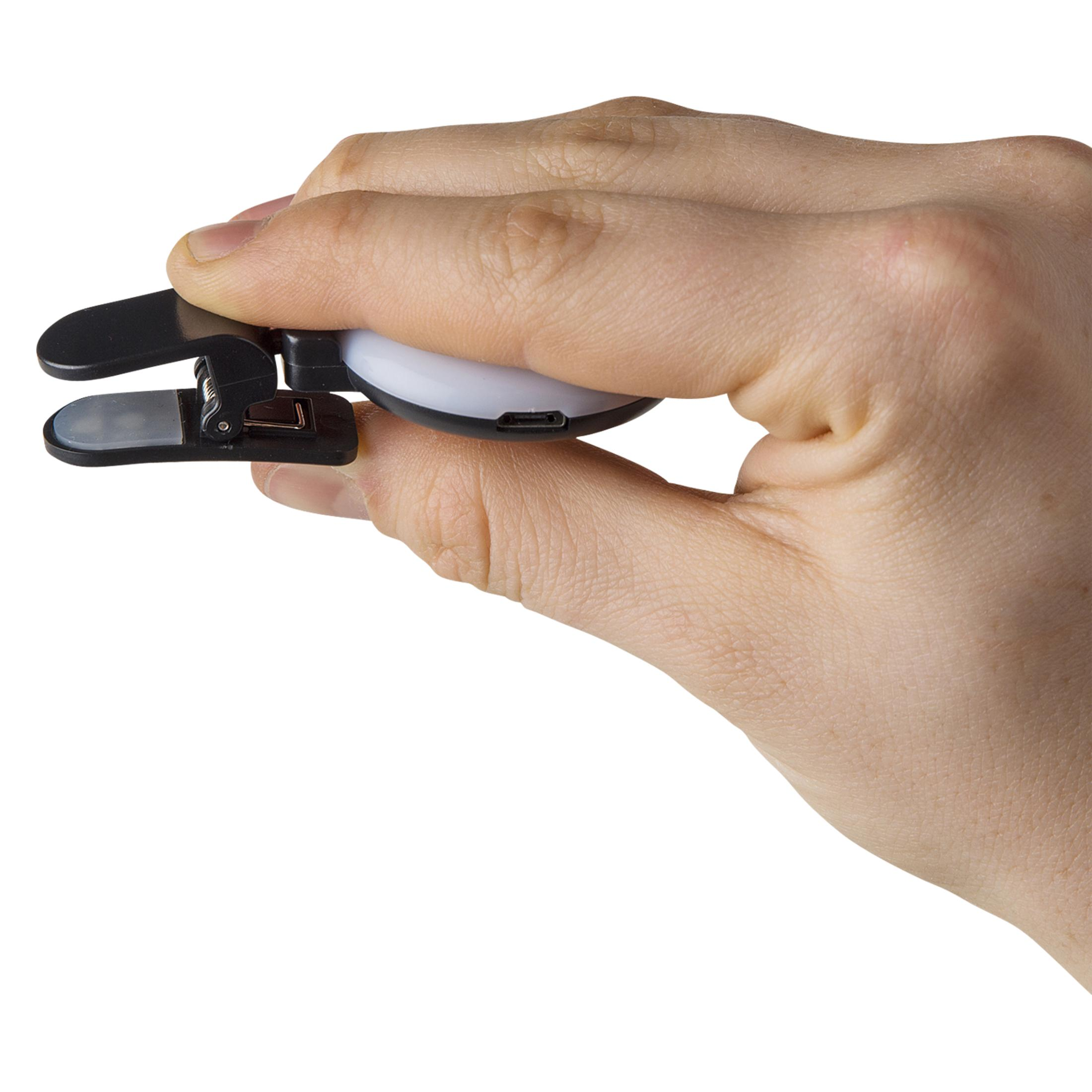 Eine Hand hält ein kleines schwarzes Leselicht mit Klemme. Ein USB-C-Anschluss ist sichtbar.