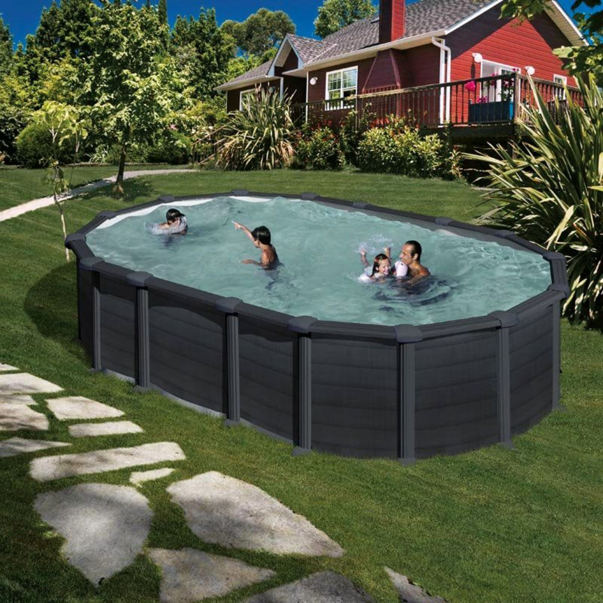 Una familia chapotea en una piscina ovalada en el patio trasero de una casa roja.