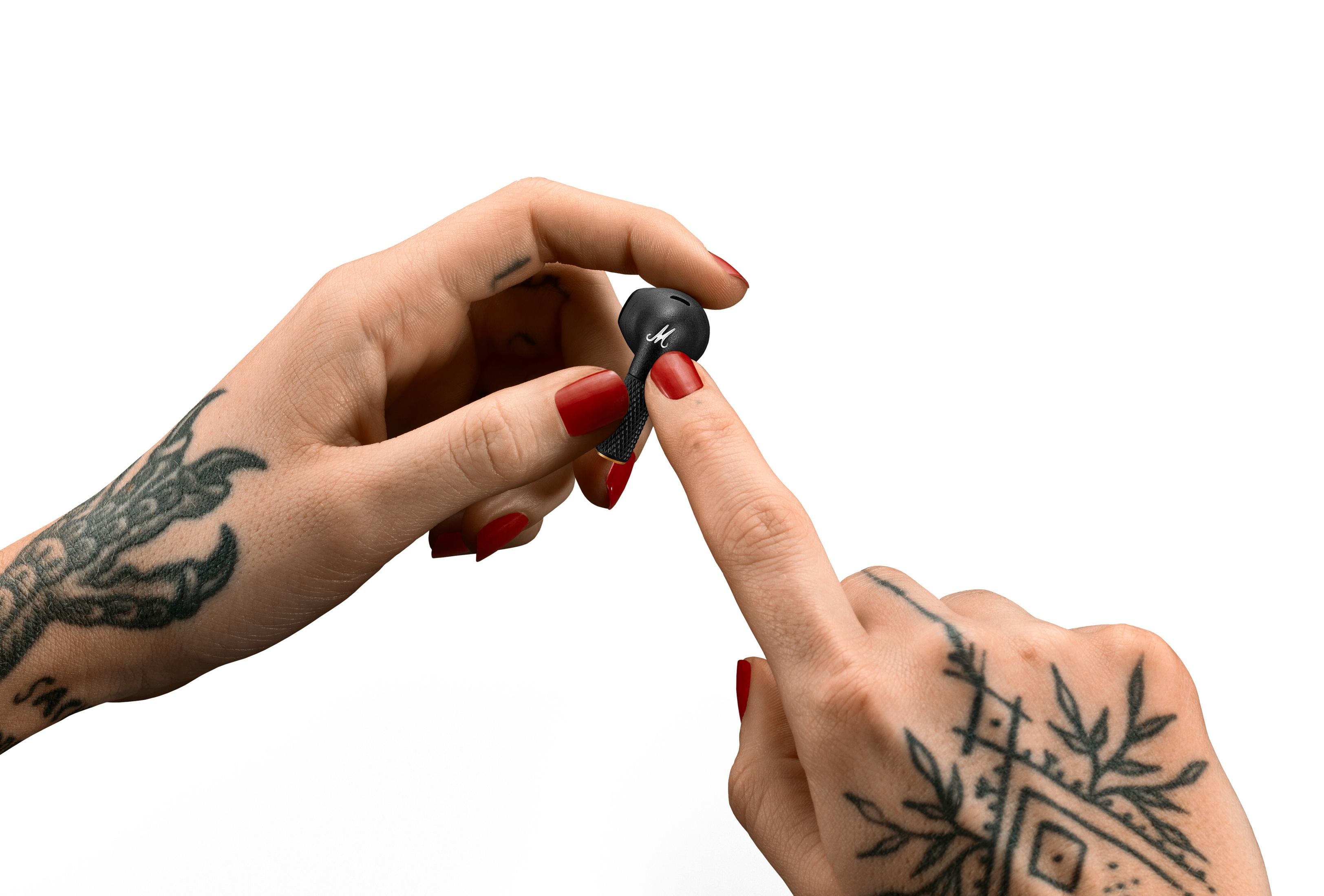 Mujer con uñas rojas sostiene un audífono Marshall negro.