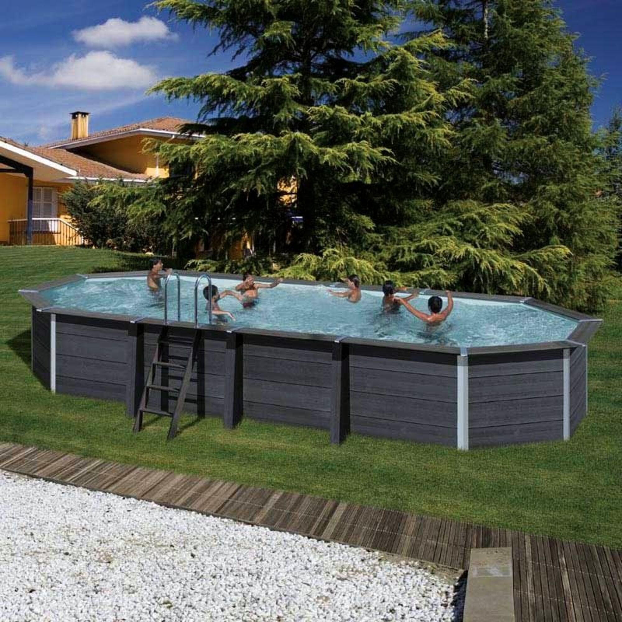 Personas chapotean en una piscina ovalada con paredes oscuras, en un día soleado.