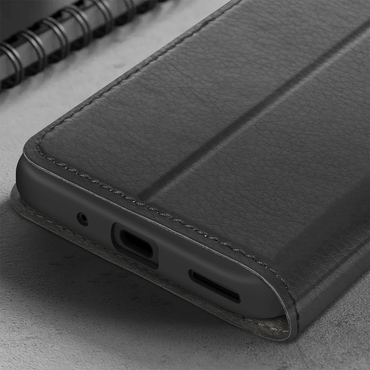 Custodia a libro in pelle nera per smartphone con porte e cuciture visibili.