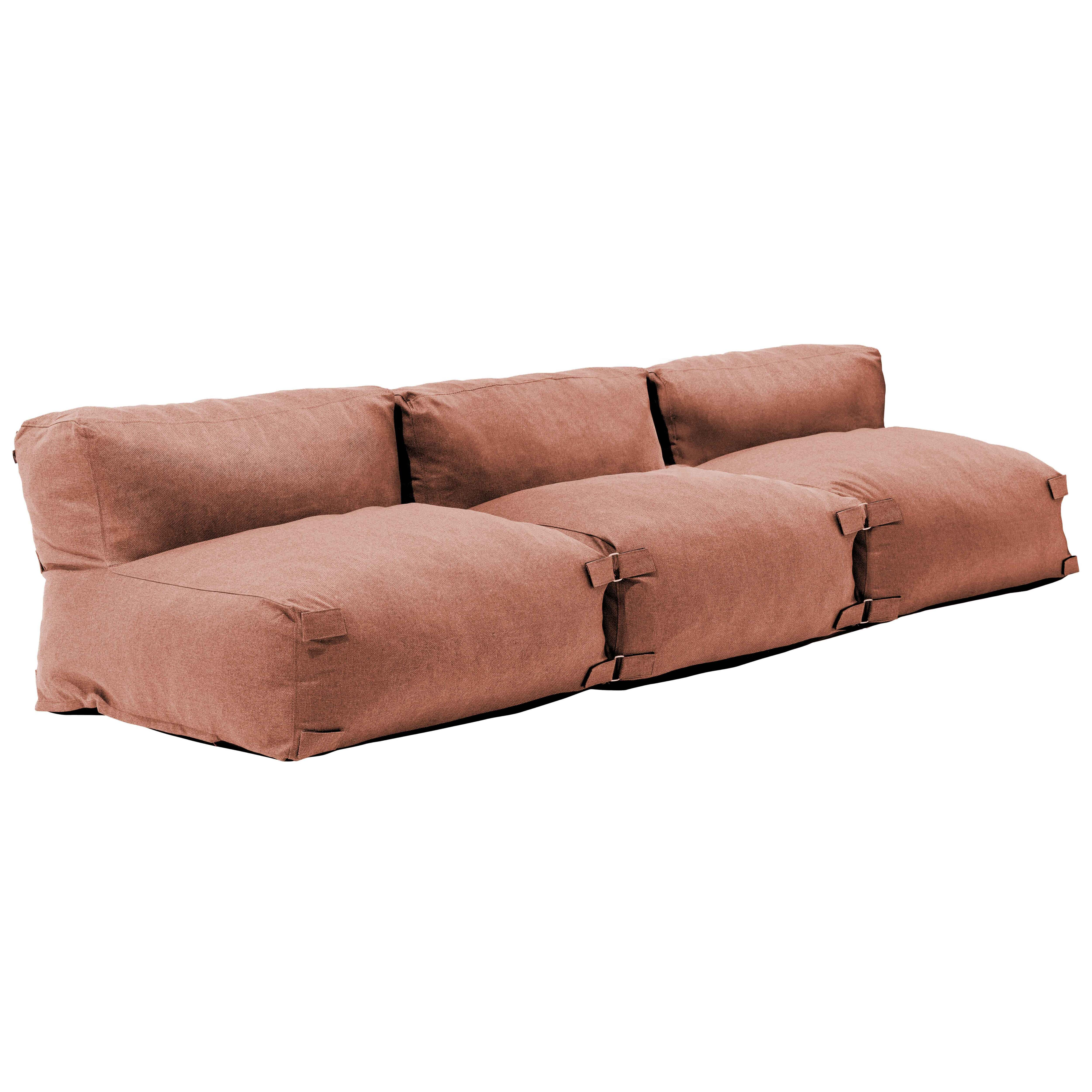 Ein korallenfarbenes, niedriges Sofa mit drei Rückenkissen und Sitzkissen.