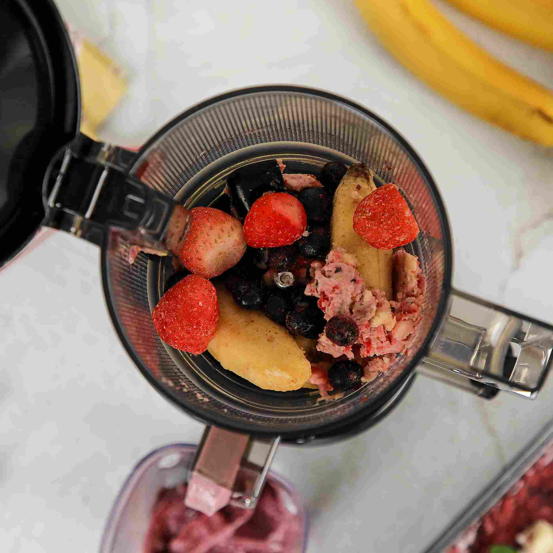Pezzi di banana, fragole e mirtilli in un estrattore.