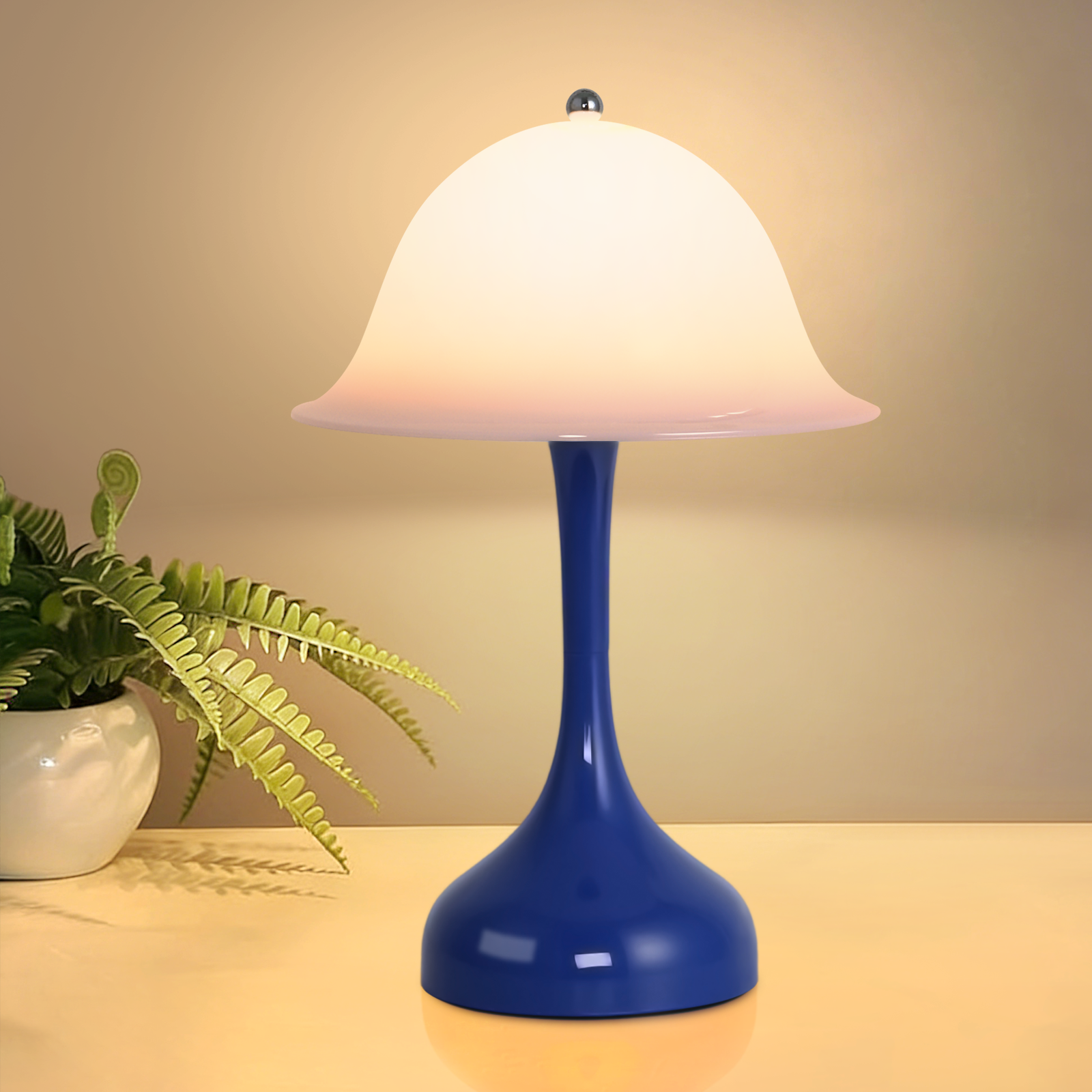 Una lampada blu con paralume bianco è accanto a una pianta verde.
