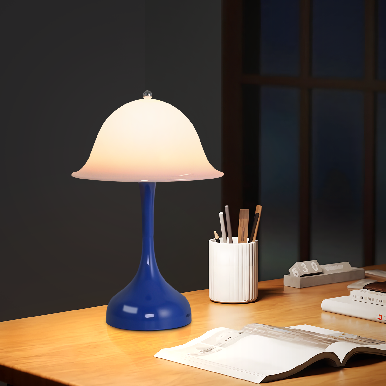 Una lampada da scrivania blu con paralume bianco su un tavolo di legno.